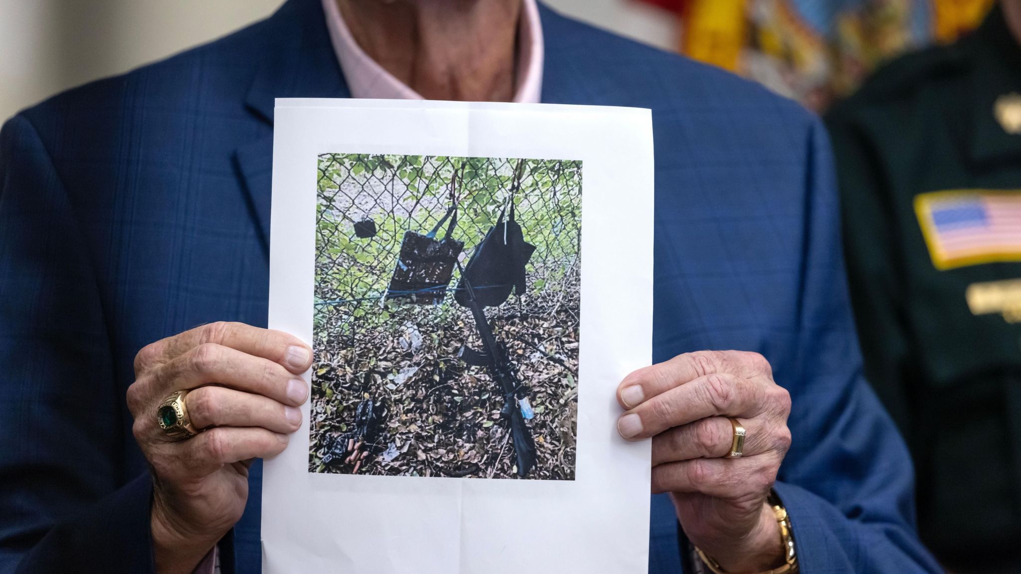 Sheriff with photo showing assault rifle with scope and two backpacks found at the golf course