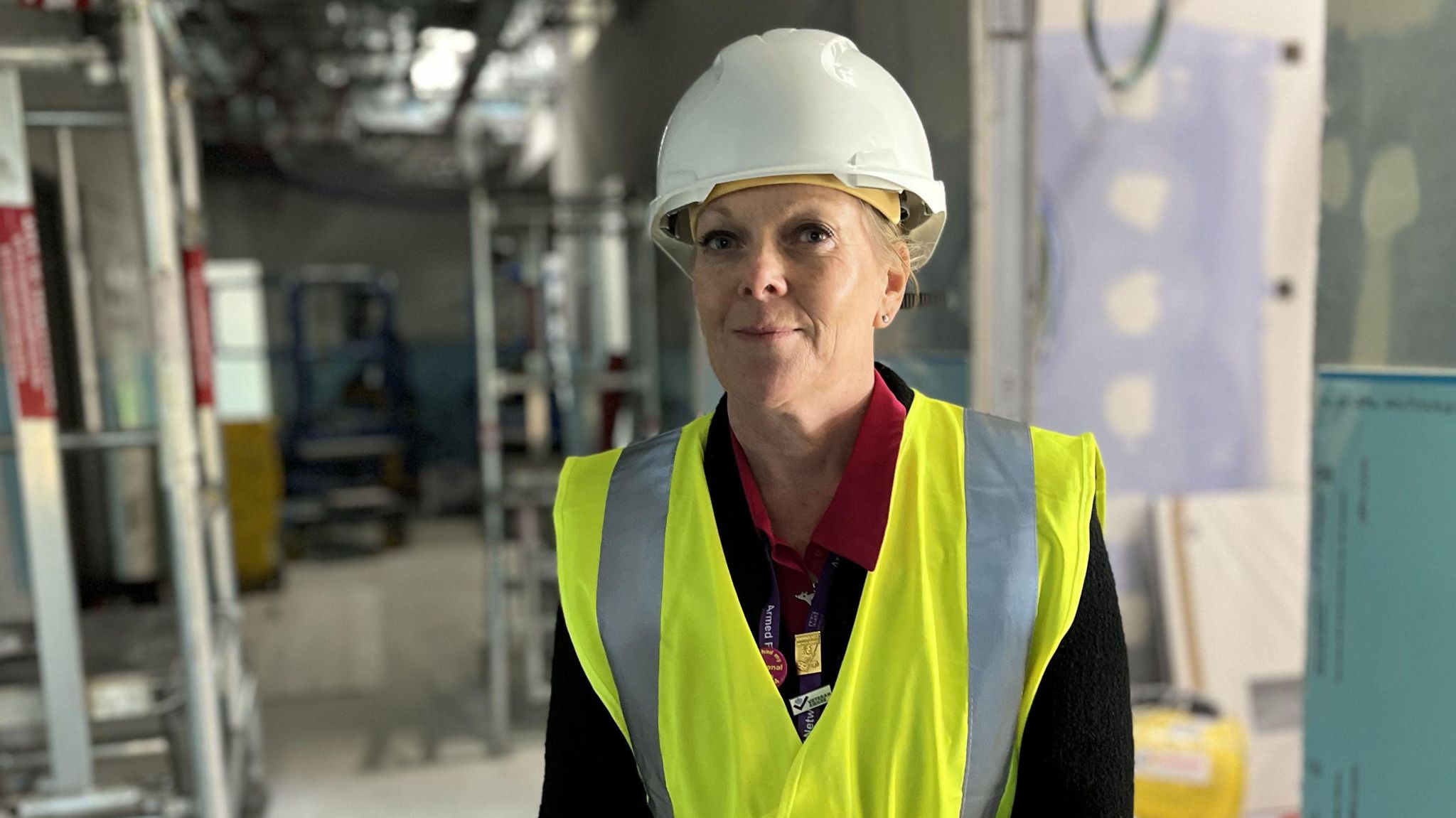 Jane Dickinson inside the new ward wearing a hard hat and high visibility vest