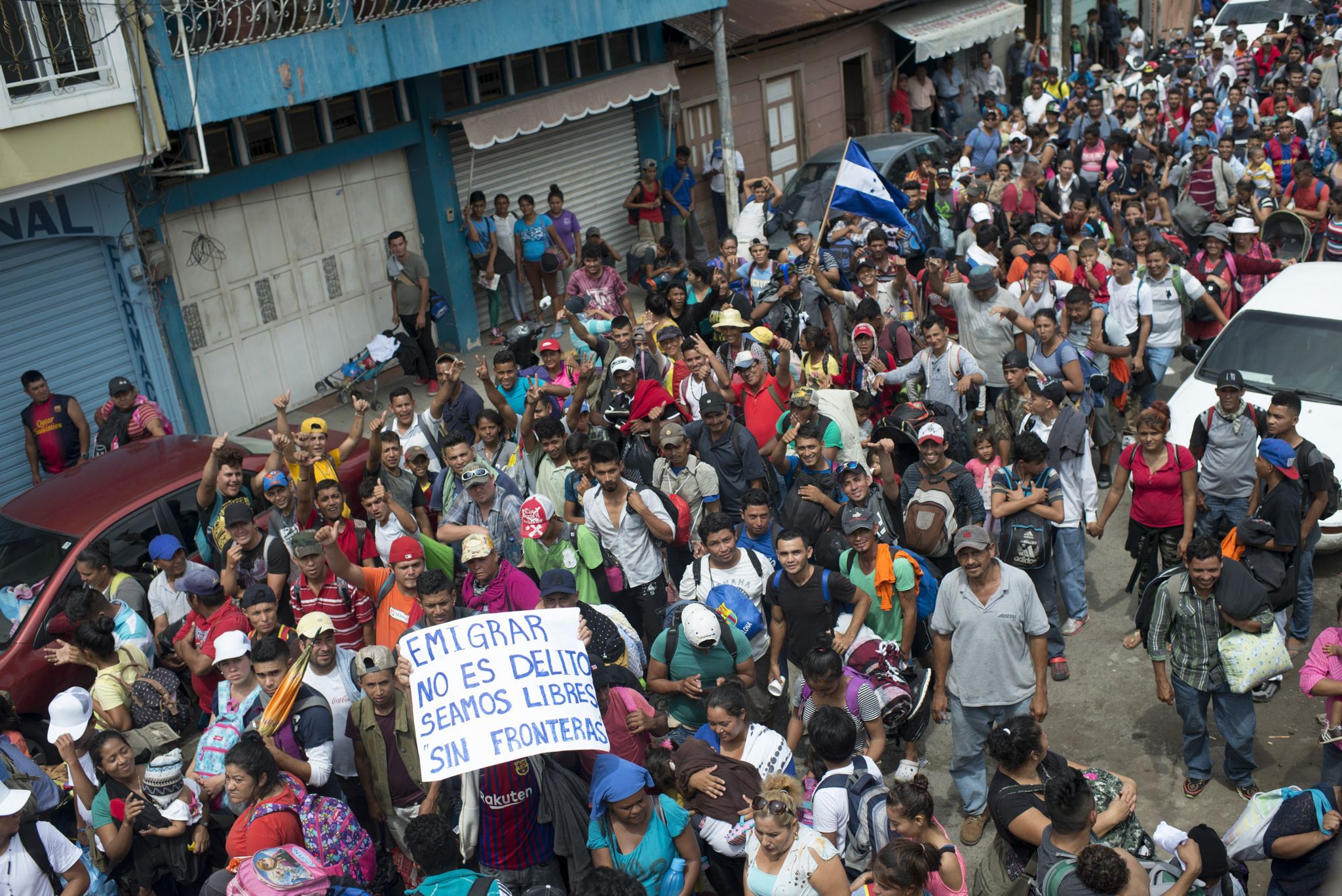 A migrant holds up a sign reading "to emigrate is not a crime, let's be free without border"