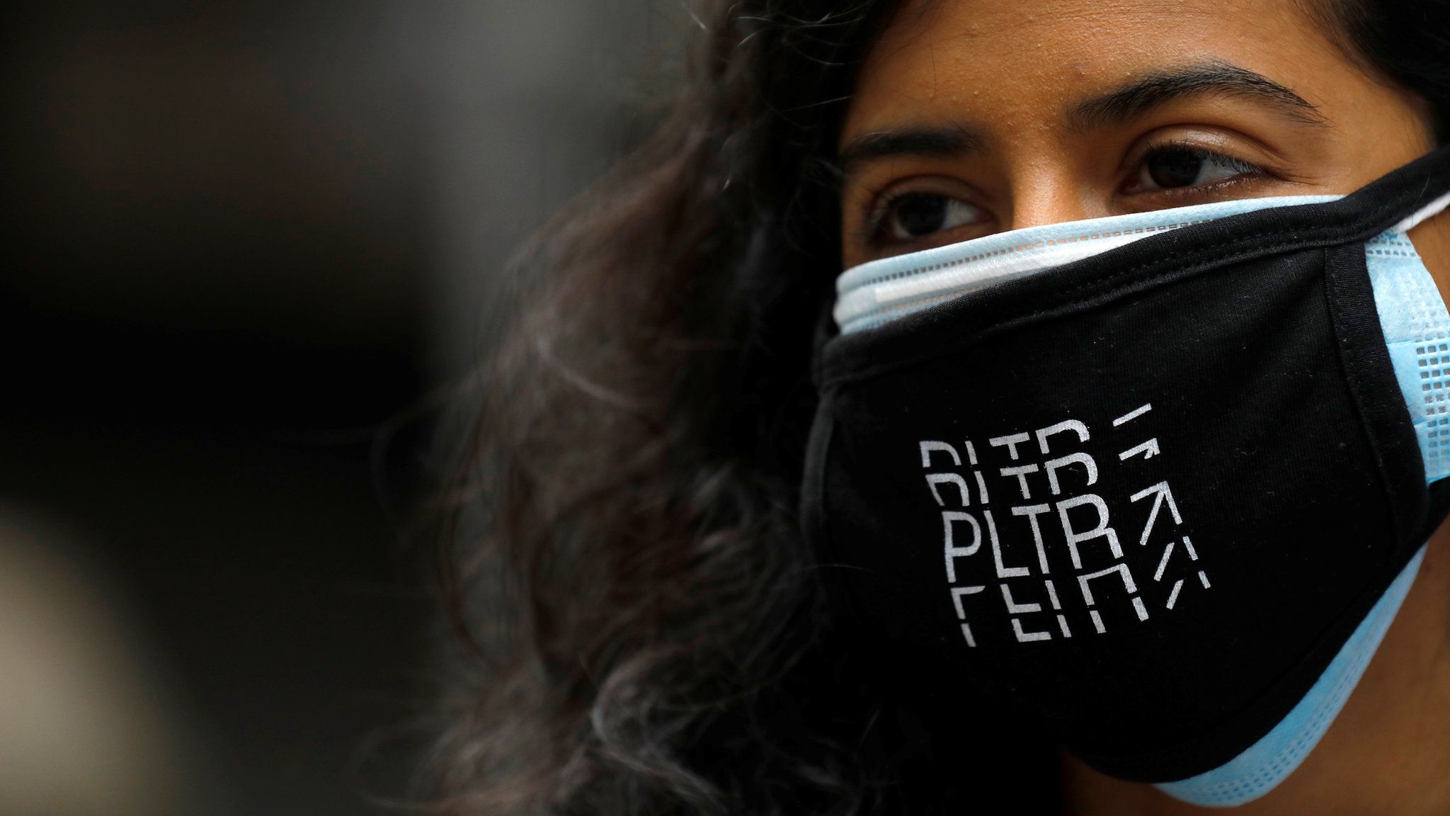 A person wears a Palantir Technologies (PLTR) face mask at the New York Stock Exchange (NYSE) on the day of the company"s initial public offering (IPO) in Manhattan, New York City, U.S., September 30, 2020.