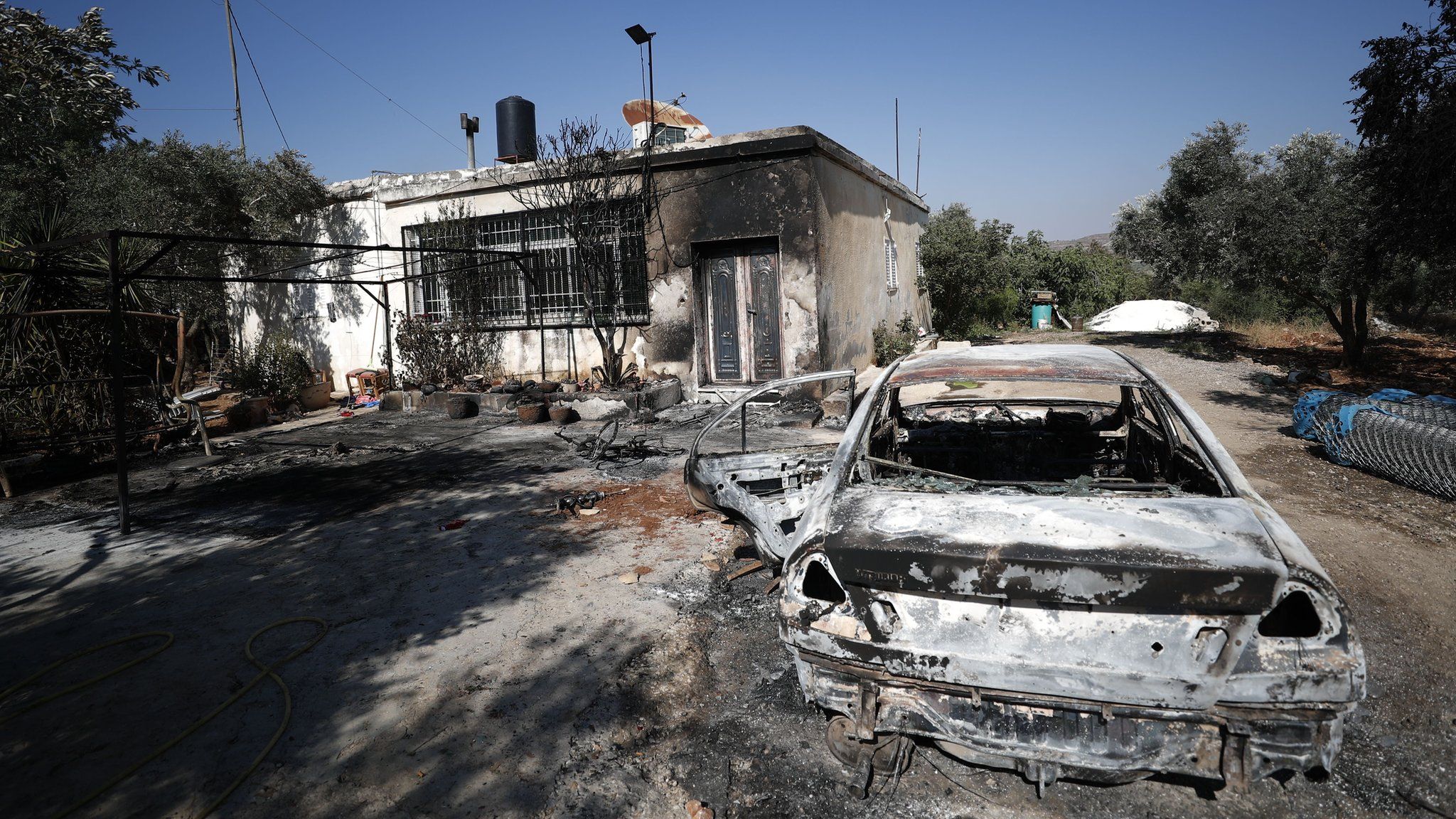 A burned out car and damaged home in the Palestinian town Turmus Aya, in the occupied West Bank, following an attack by Israeli settlers (21 June 2023)
