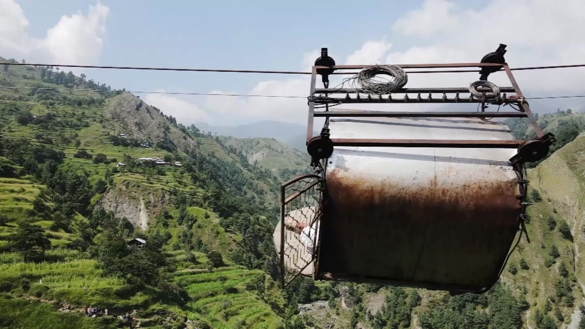 Drone footage showing the cable car up close, dangling over the ravine.