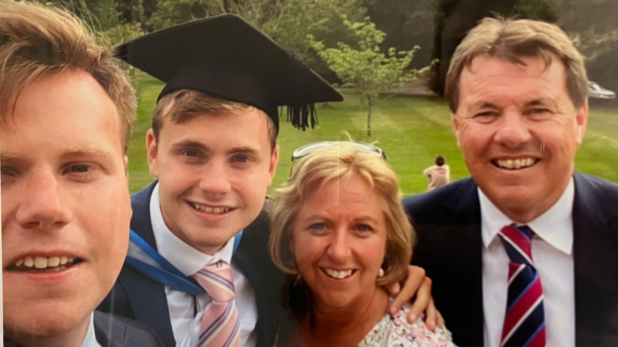 Jack O'Sullivan at his graduation. He is smiling with his mum, dad, and older brother