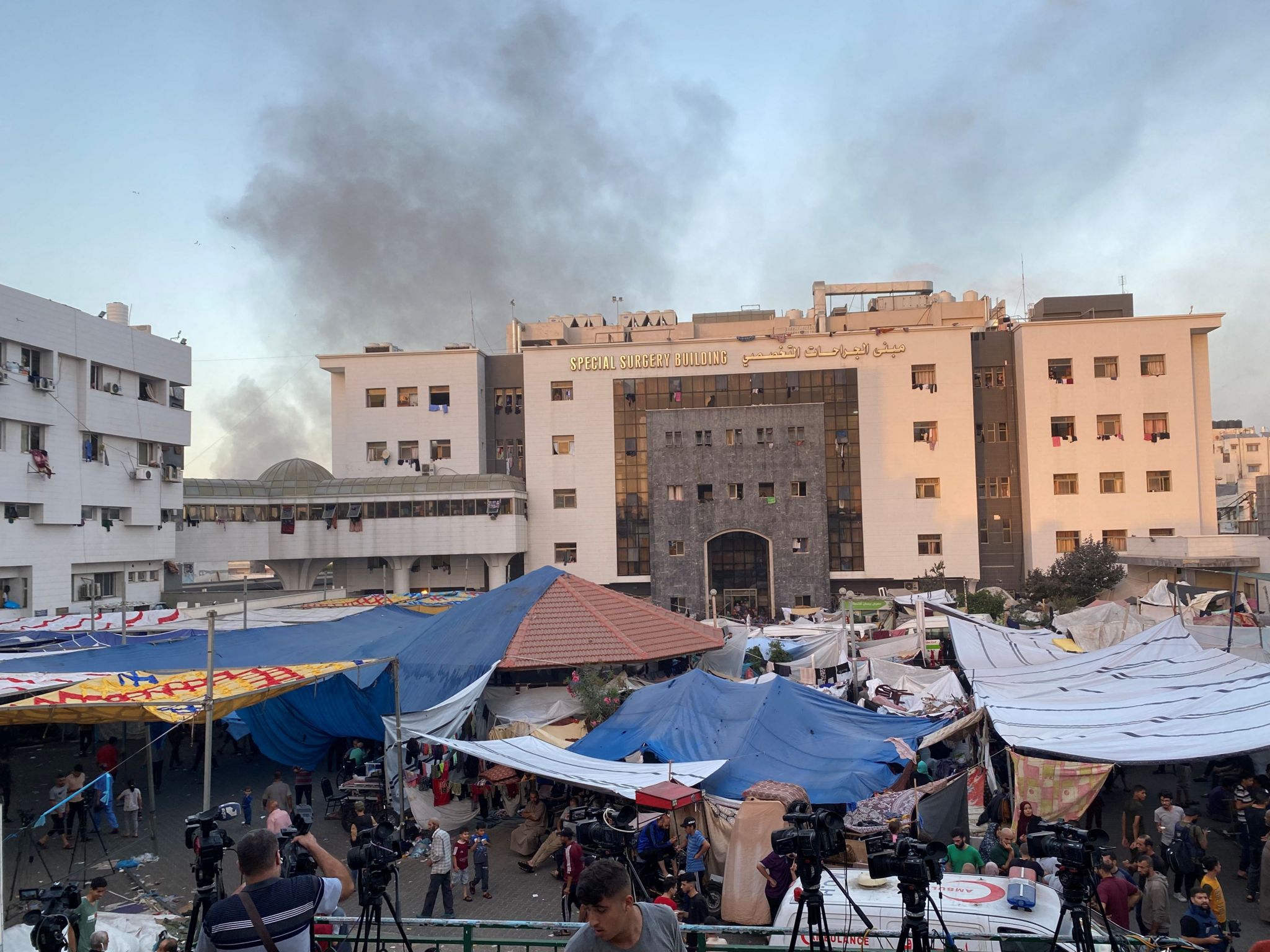 Al-Shifa Hospital in Gaza with smoke billowing in the back and tents in front