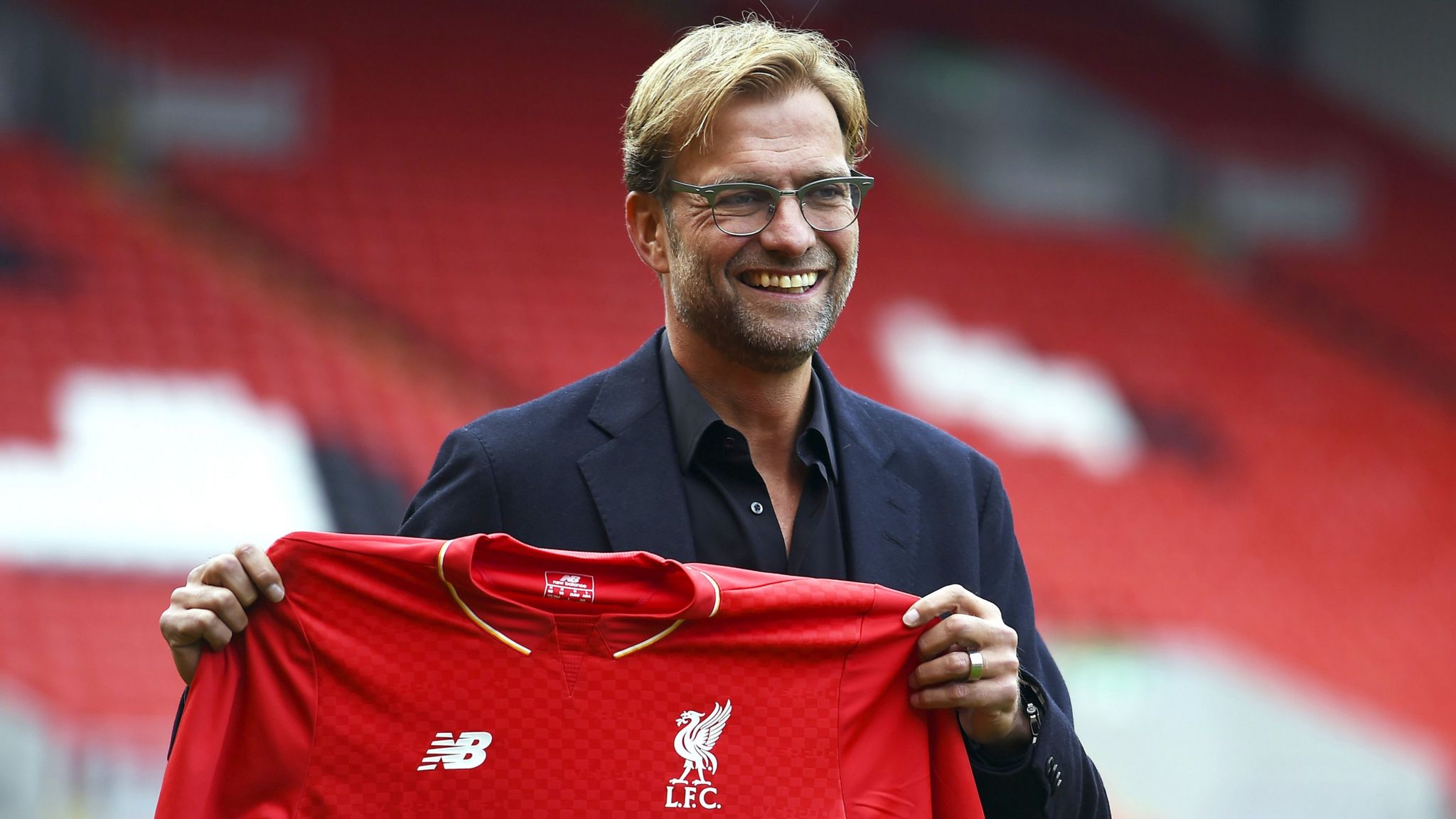 Jurgen Klopp holds up a Liverpool shirt