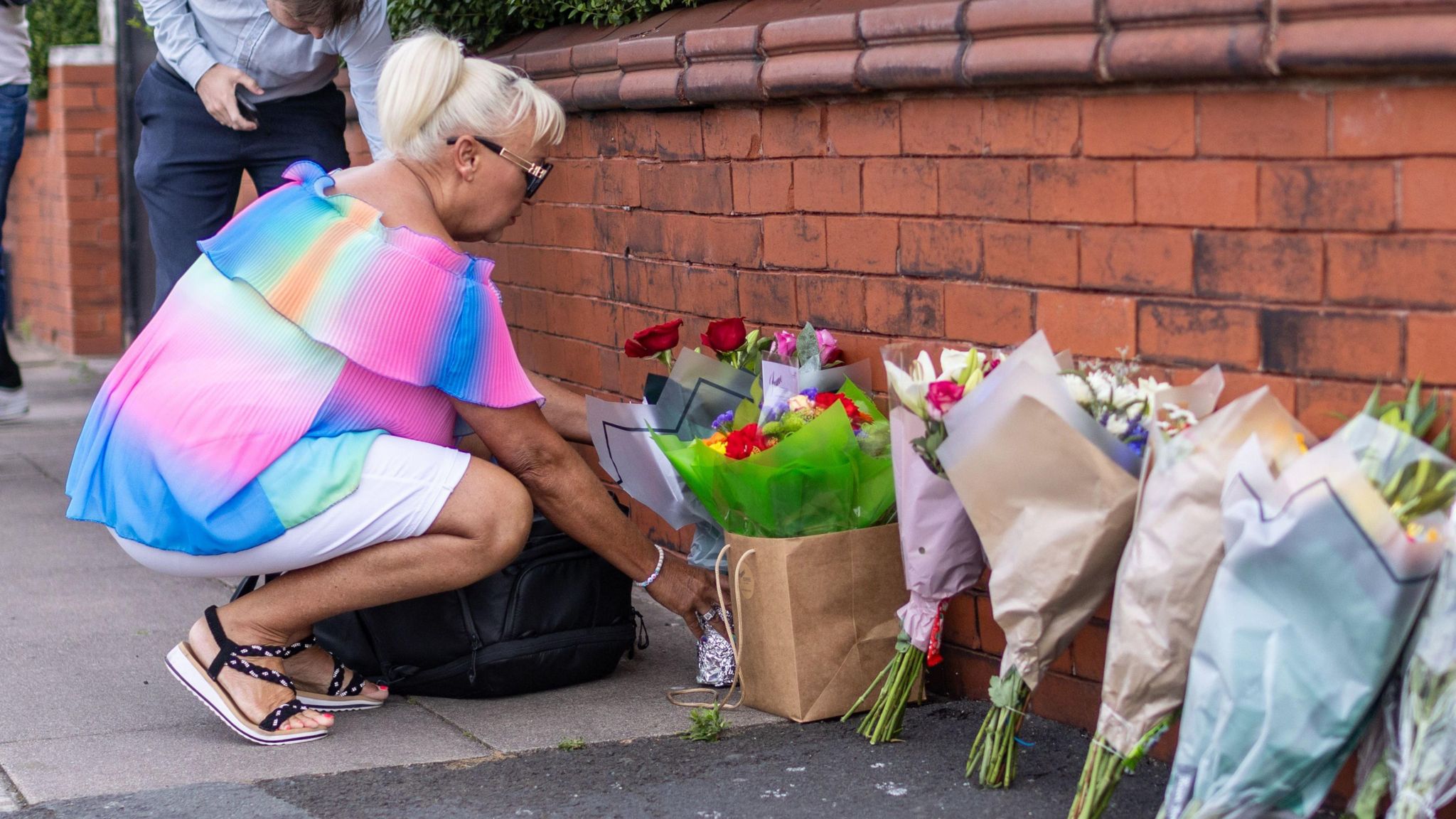 A person leaves flowers near the scene in Hart Street, Southport, where two children died