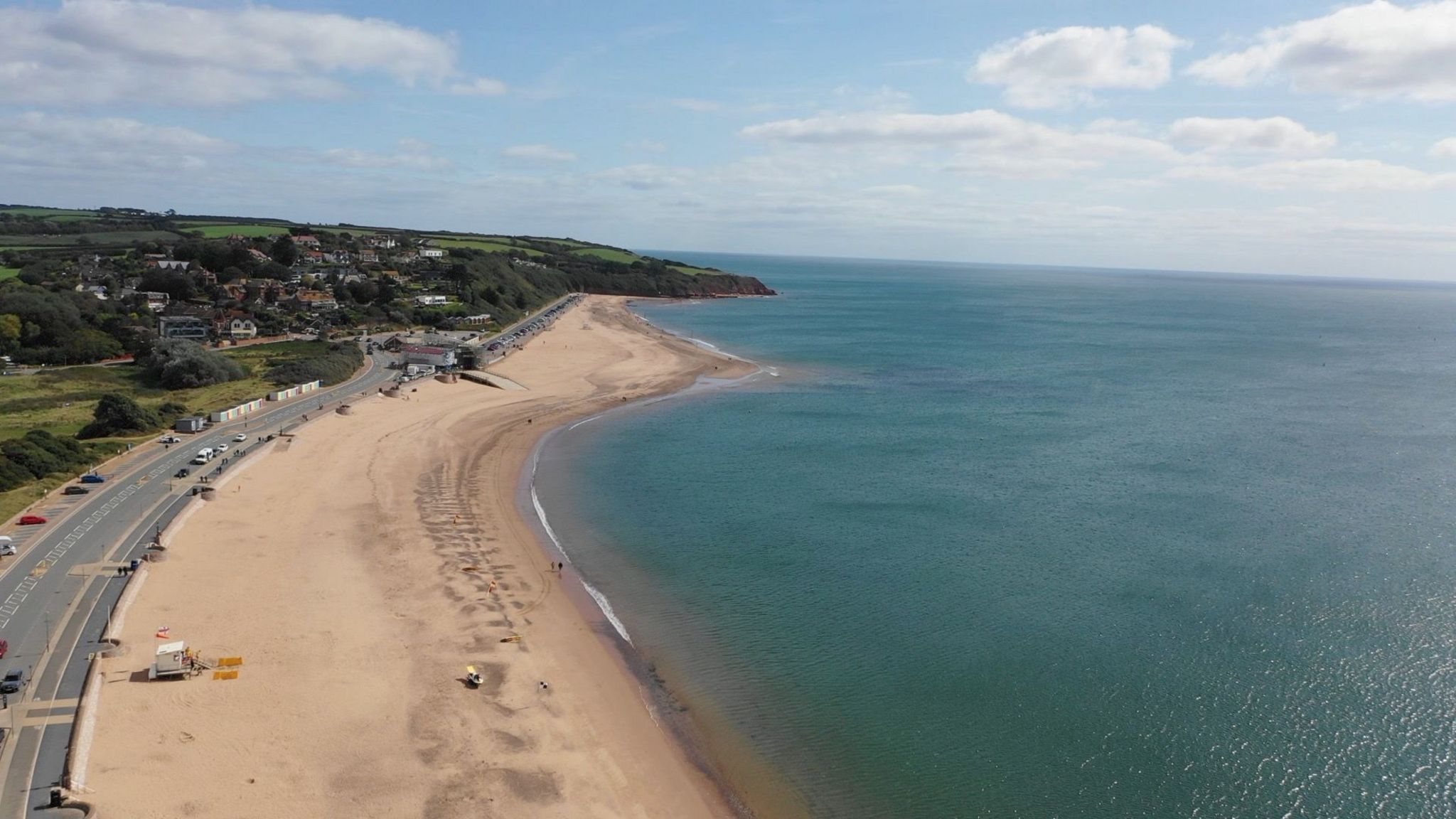 Aerial view on the beach at Exmouth on the East Devon coast. The view shows a bright day, blue sea and a stretch of golden sand. An RNLI cabin is also visible.