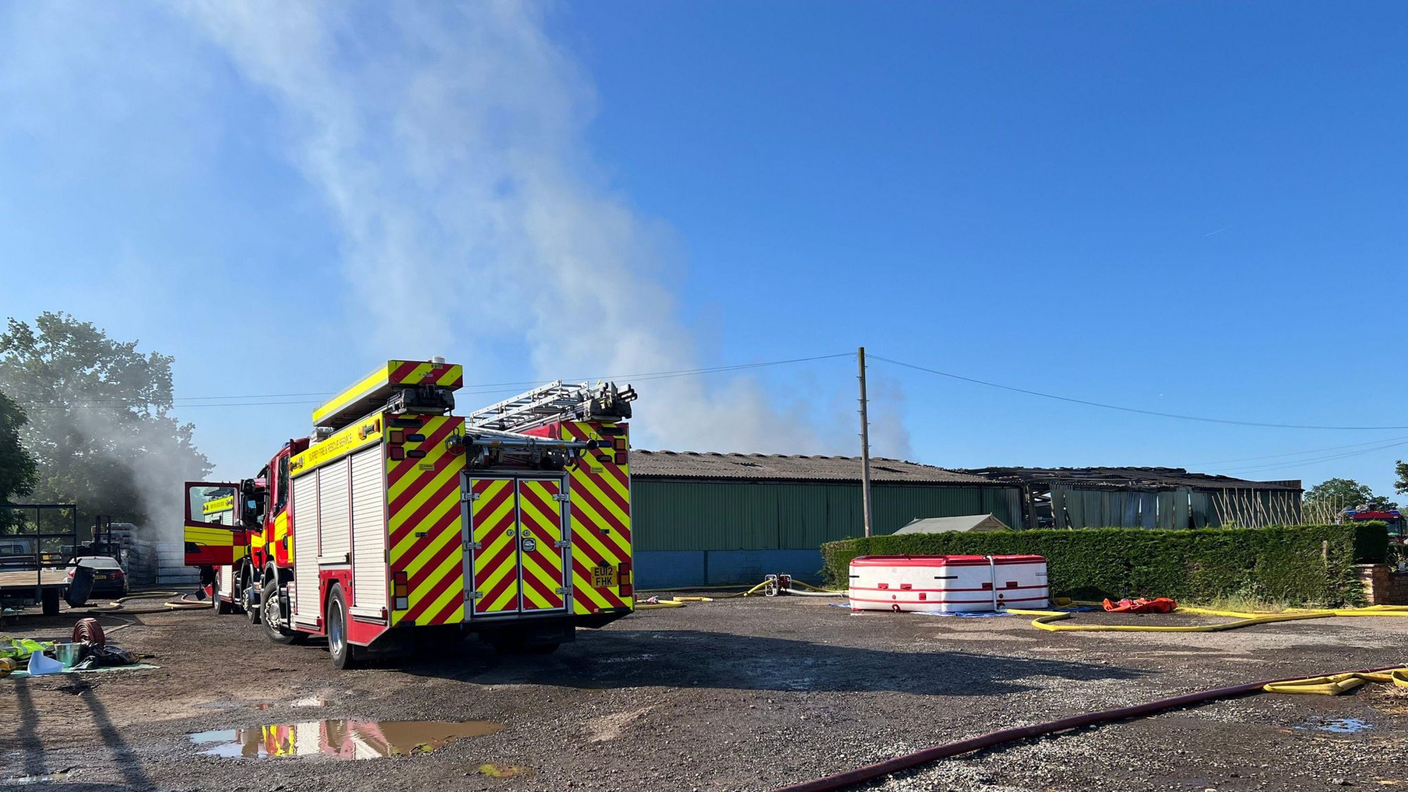 A fire engine seen from the back with the smoking barn in the background