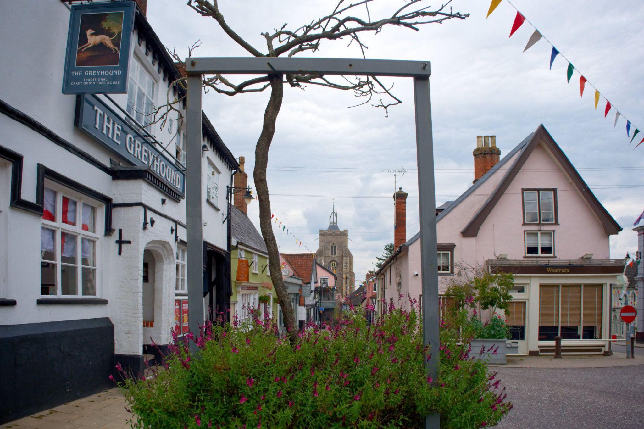Street in Diss with showing buildings painted pink and white, with bunting hanging above the street