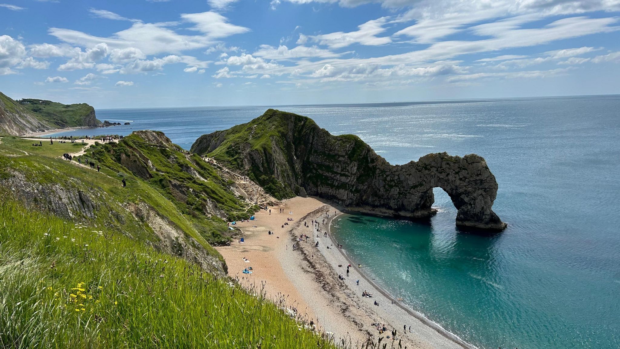 TUESDAY - A sunny day overlooking the natural arch at Durdle Door with people lying on the beach