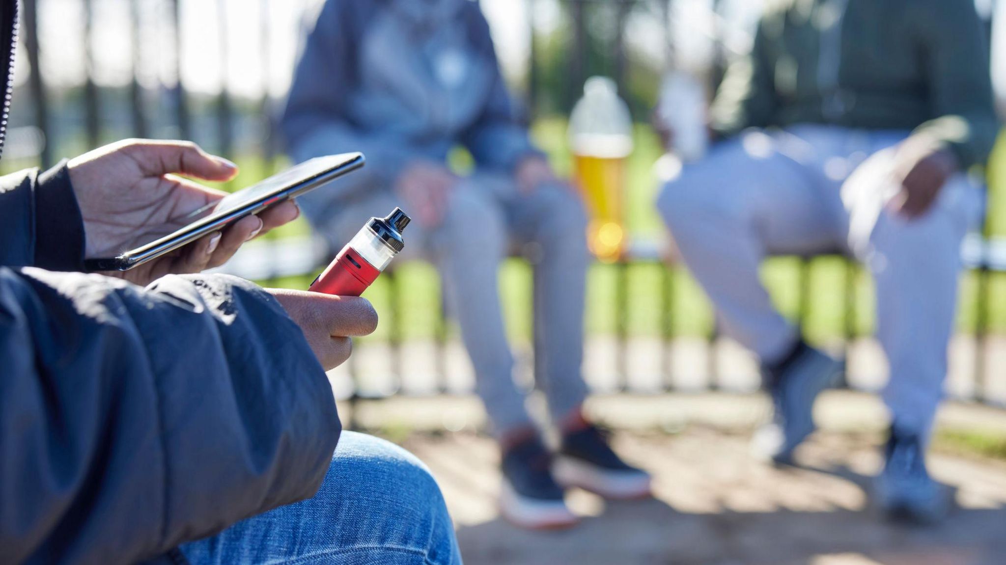 Teenagers in a park vaping and drinking