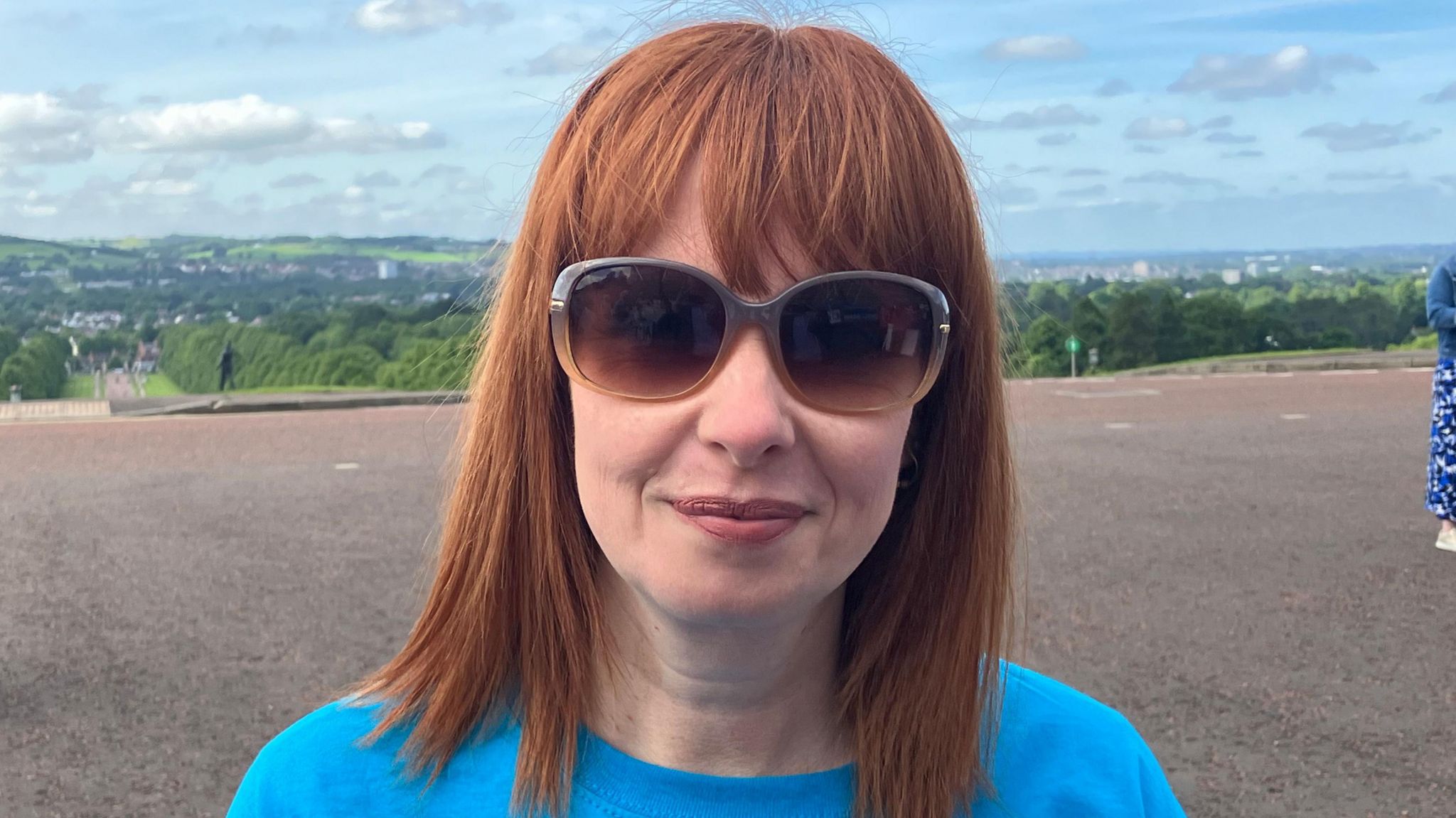 Alma White wears a blue t-shirt and sunglasses outside the Stormont protest