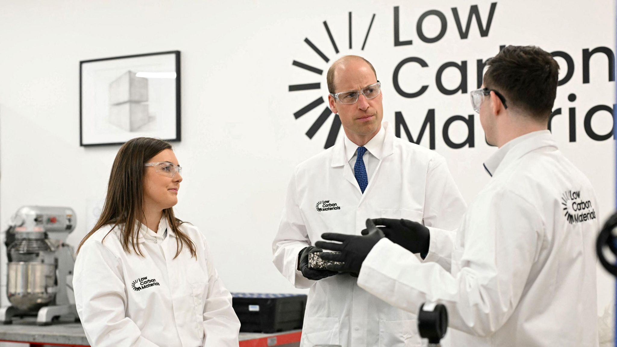 Prince William with two members of staff wearing lab coats