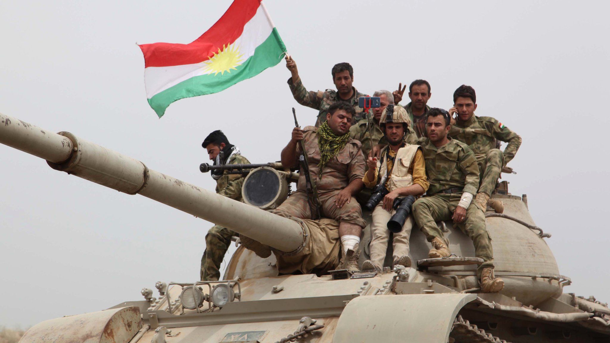 Kurdish forces sit on top of a tank waving the Kurdish flag after recapturing the town of Bashir on 1 May 2016