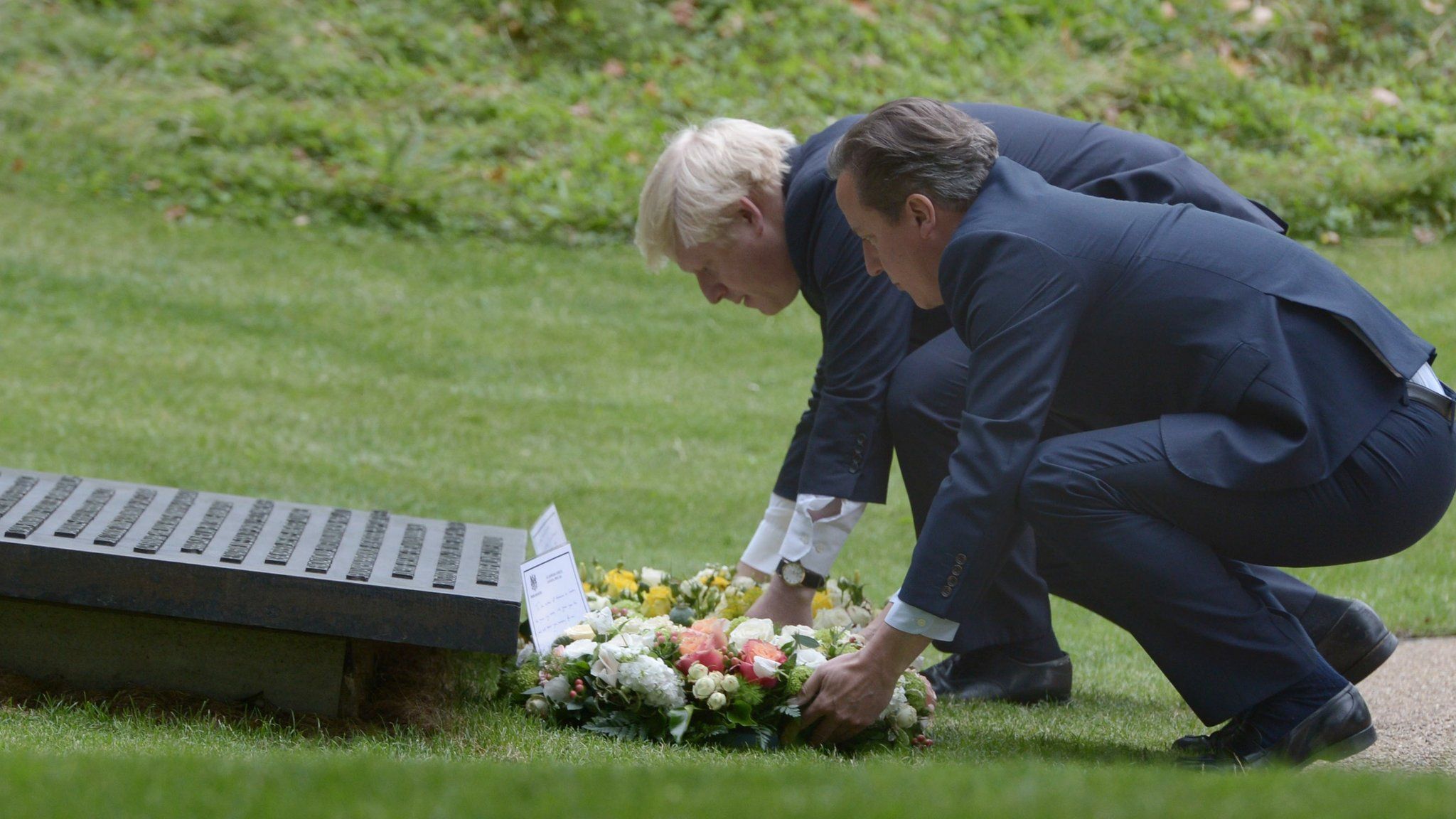 London Mayor Boris Johnson (left) and British Prime Minister David Cameron carry wreathes at the July 7 memorial in Hyde Park, London