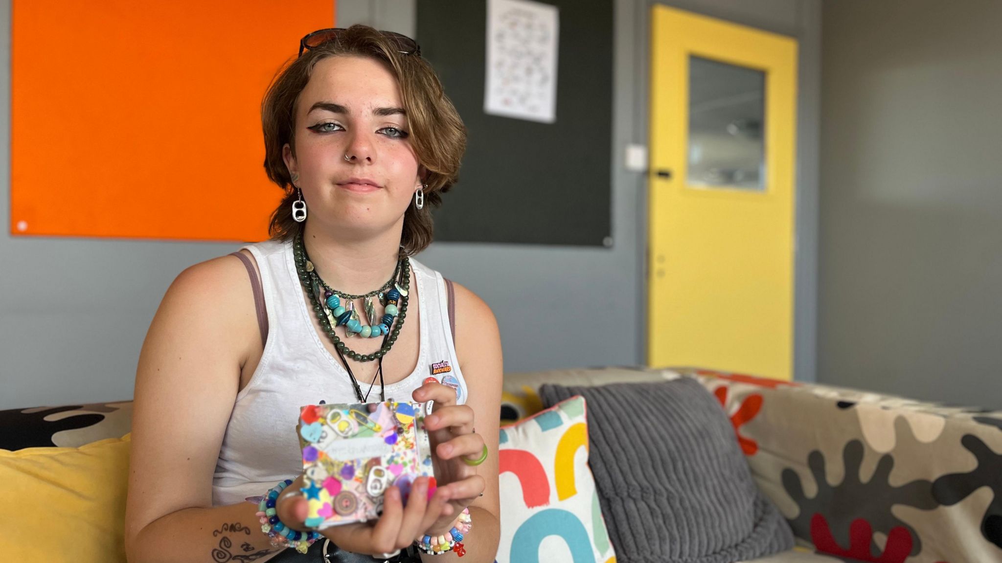 A young person holds a small colourful booklet to the camera