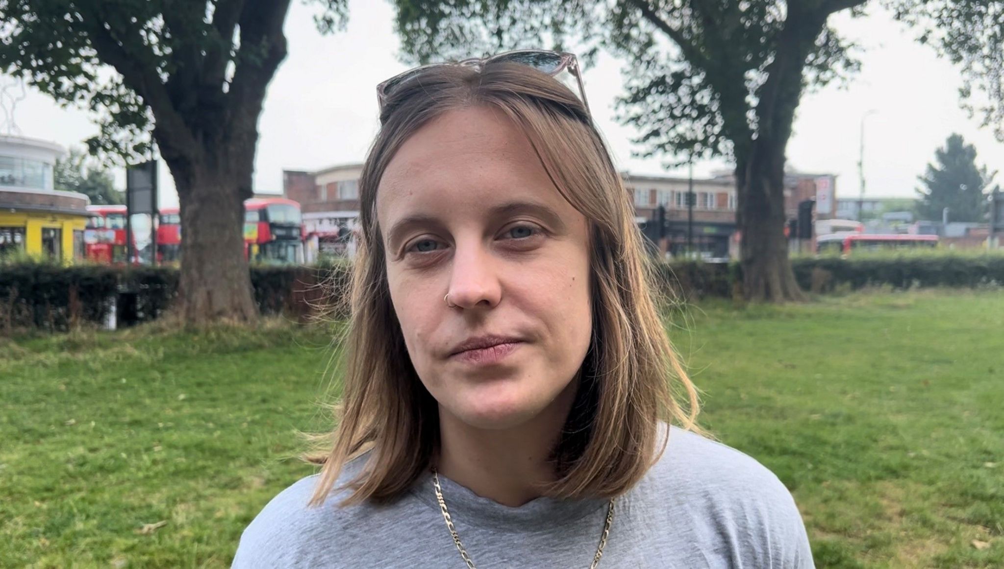 Dr Caitlin Clunie-O’Connor standing in a park wearing a grey top and with sunglasses on her head