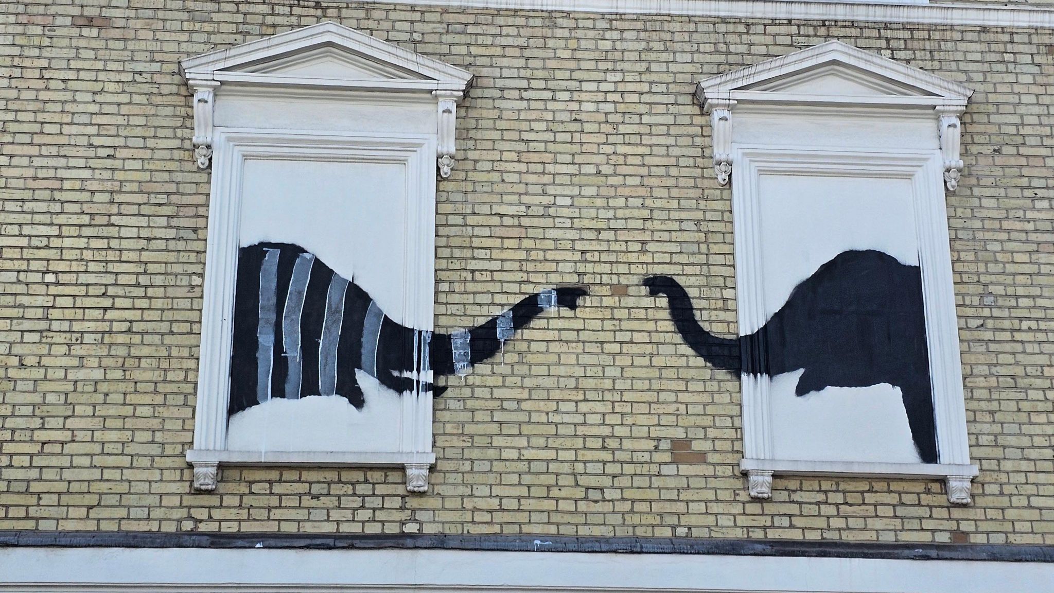 Banksy mural of two elephants, one covered in white stripes