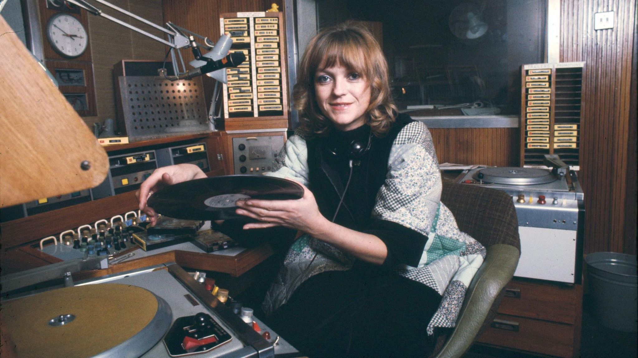 Annie Nightingale putting a record on a record player in a radio studio in November 1976