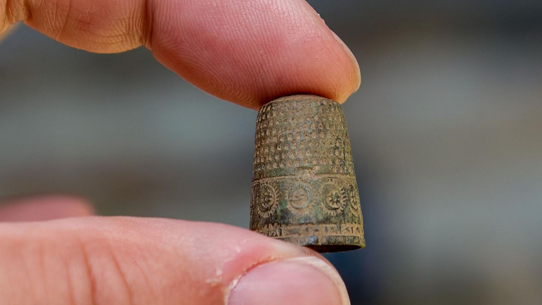 Patterned thimble being held between finger and thumb