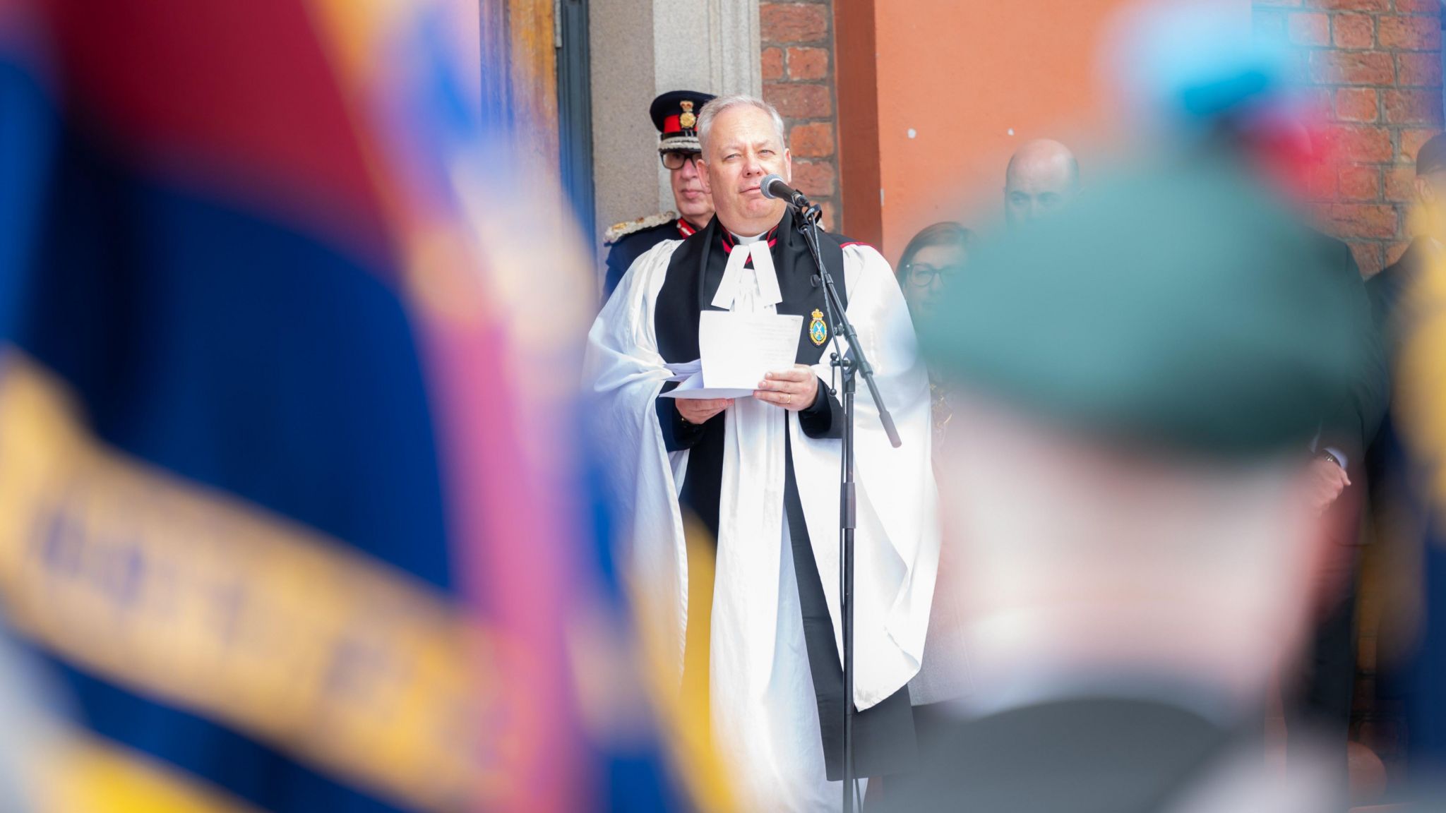 Reverend Canon Dr Crispin Pailing standing next to a microphone about to make a speech for a recent D-Day veterans parade