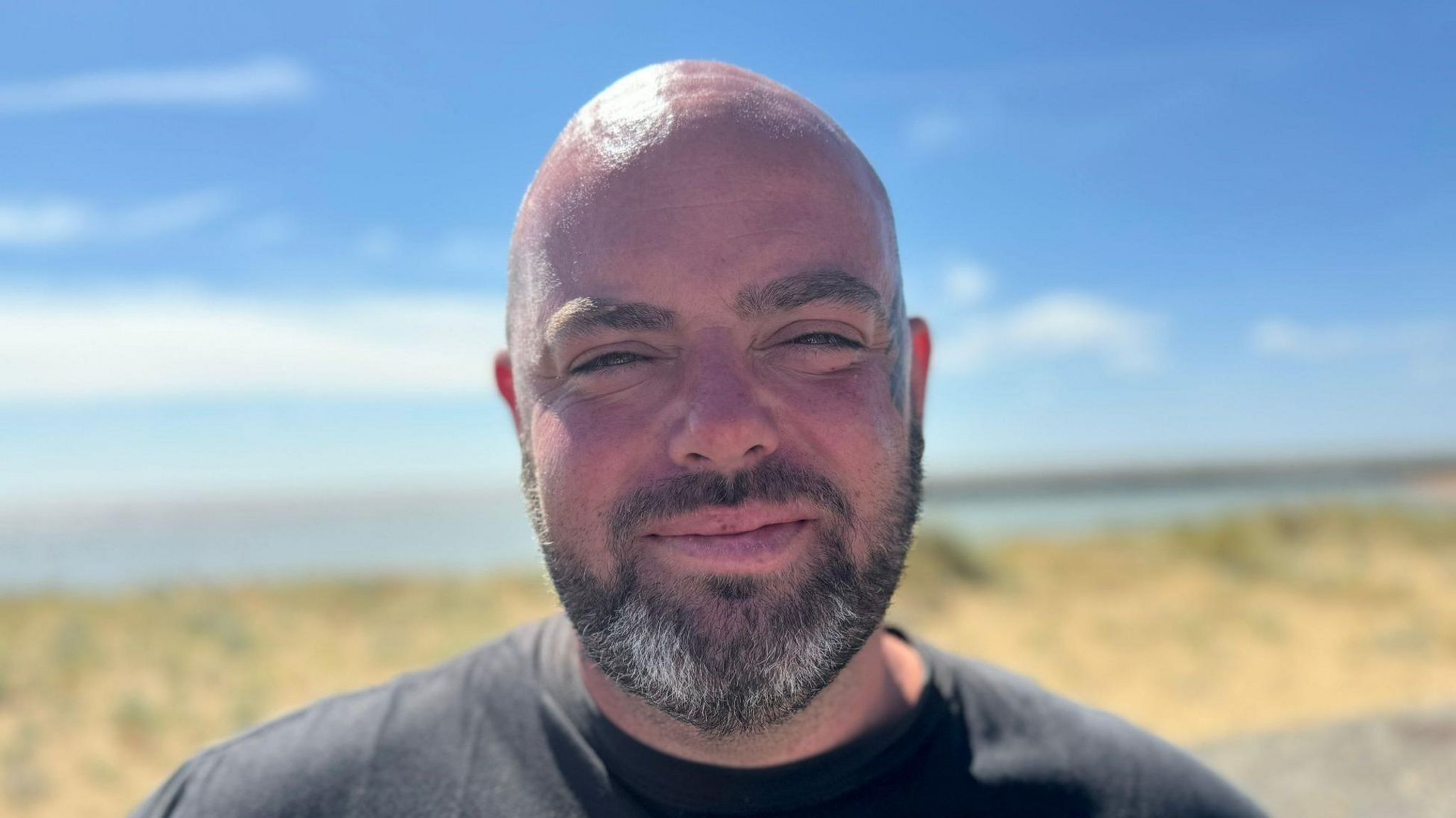 Bradley Thompson standing in front of Jaywick beach