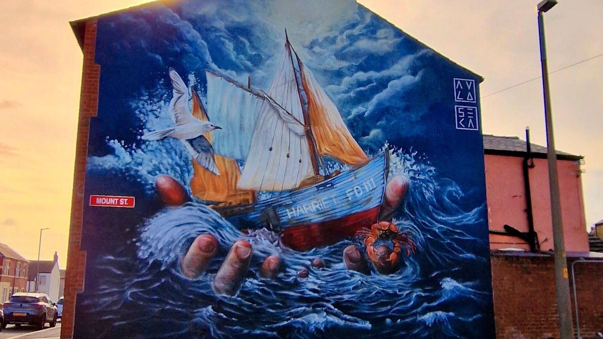 A mural on the side of a building that shows a fishing boat held in a pair of hands