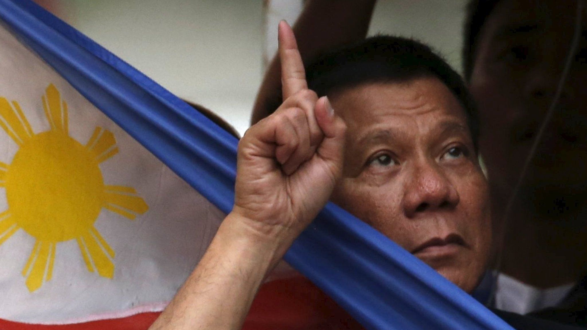 Rodrigo Duterte holds a national flag during election campaigning in Manila on 27 April