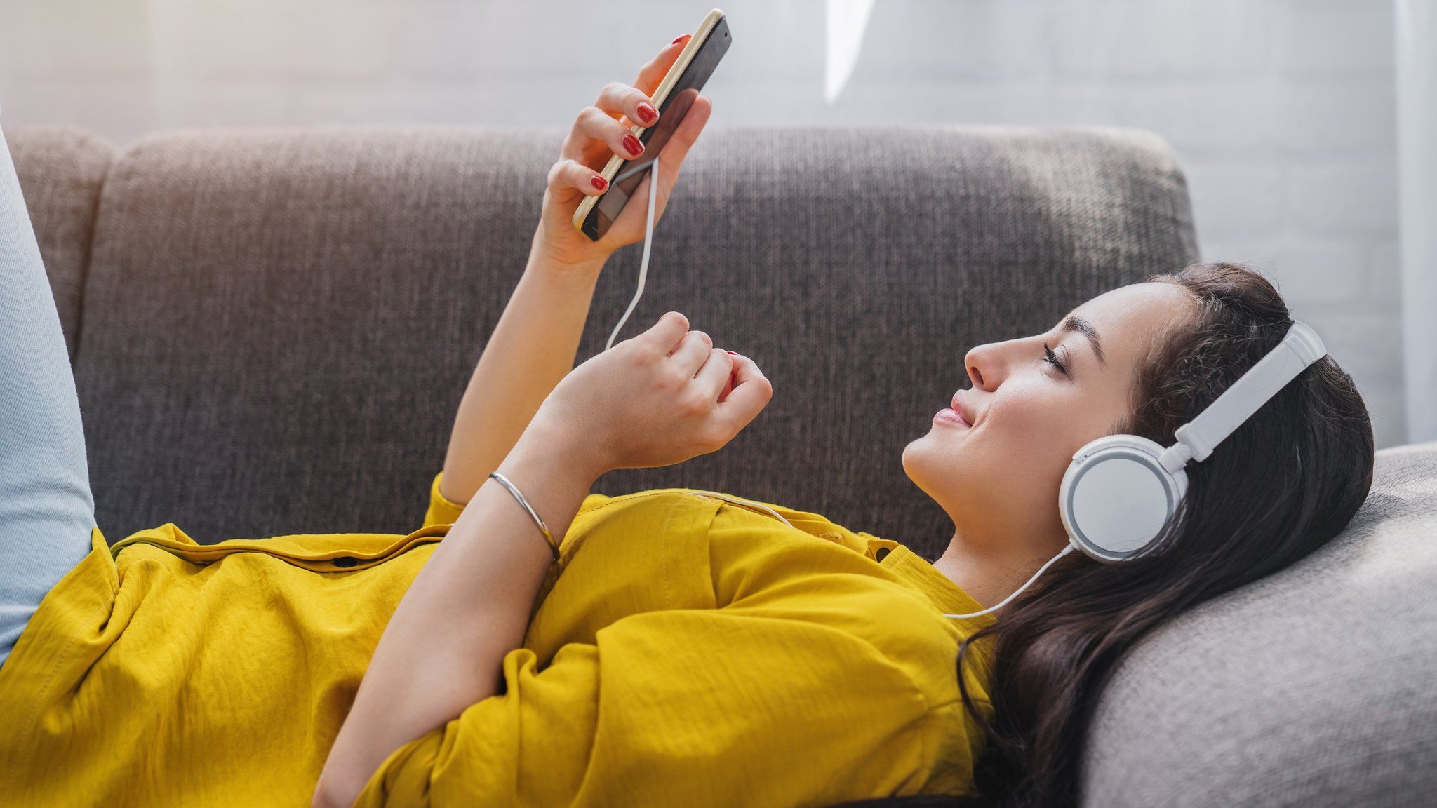 A woman listening to music using headphone (stock image)