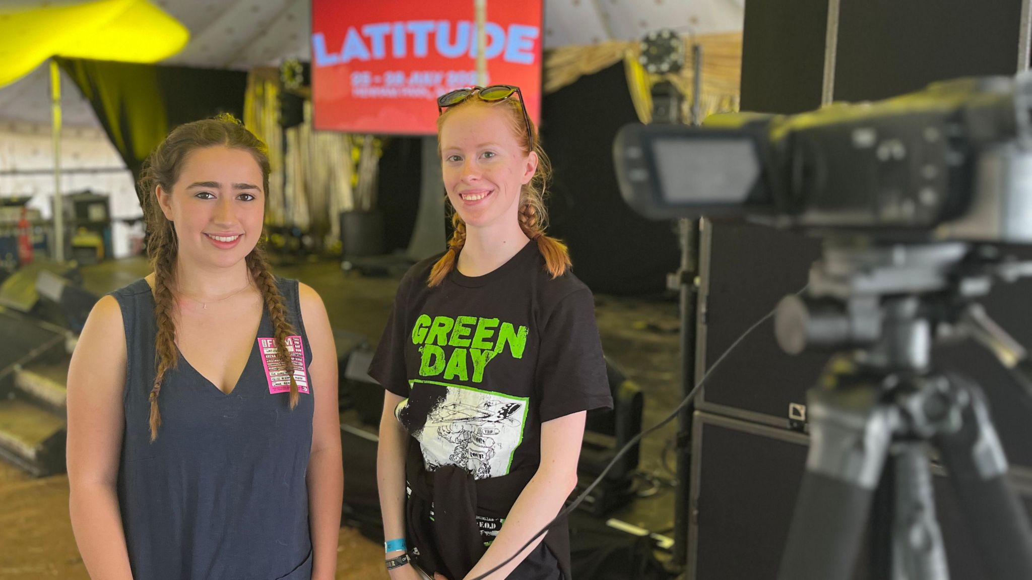 Lara Bentley and Lucy Potter stand in front of a stage with a TV camera in the foreground