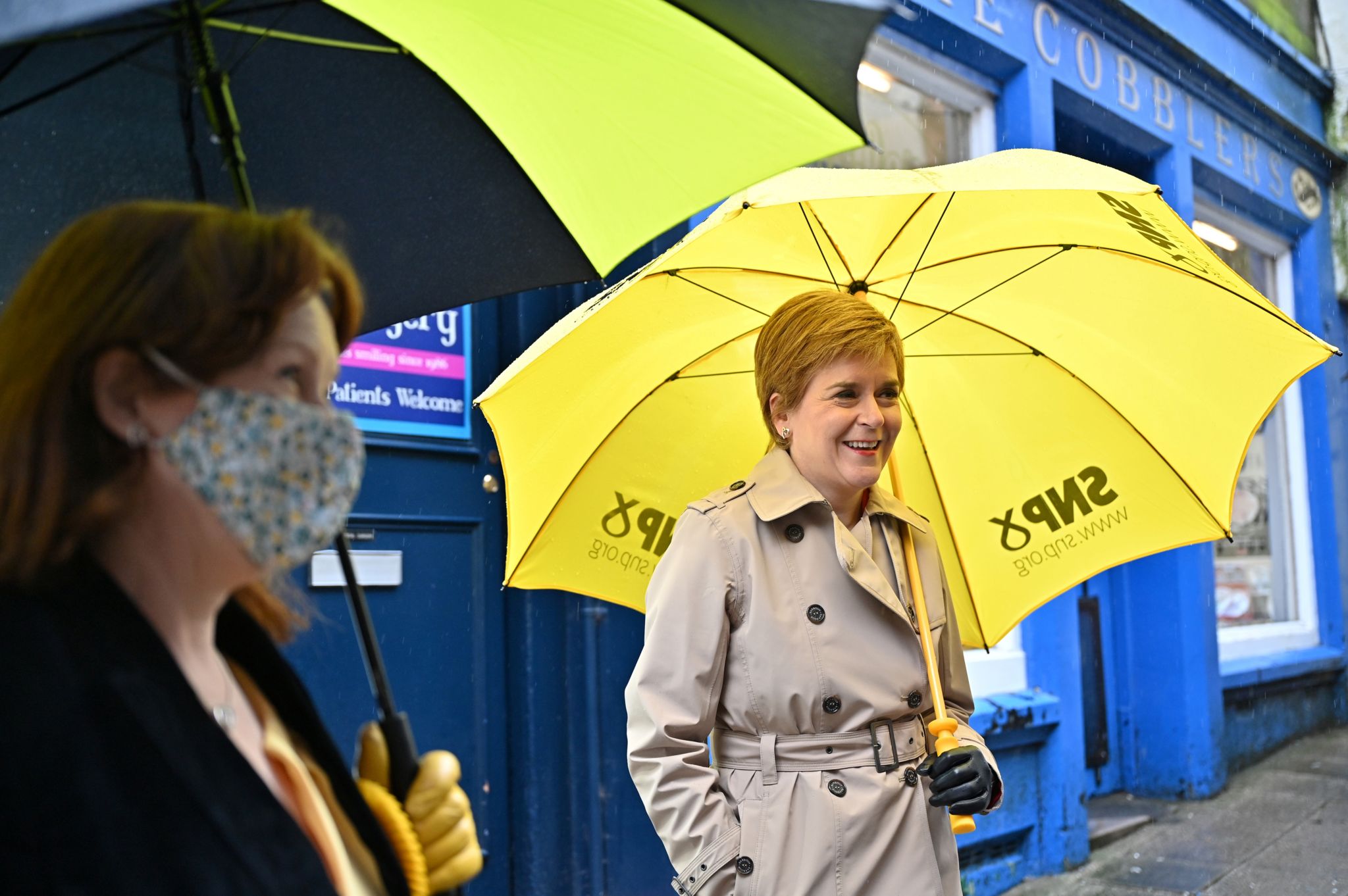 SNP leader Nicola Sturgeon holds a yellow SNP umbrella while outside shops in Dumfries