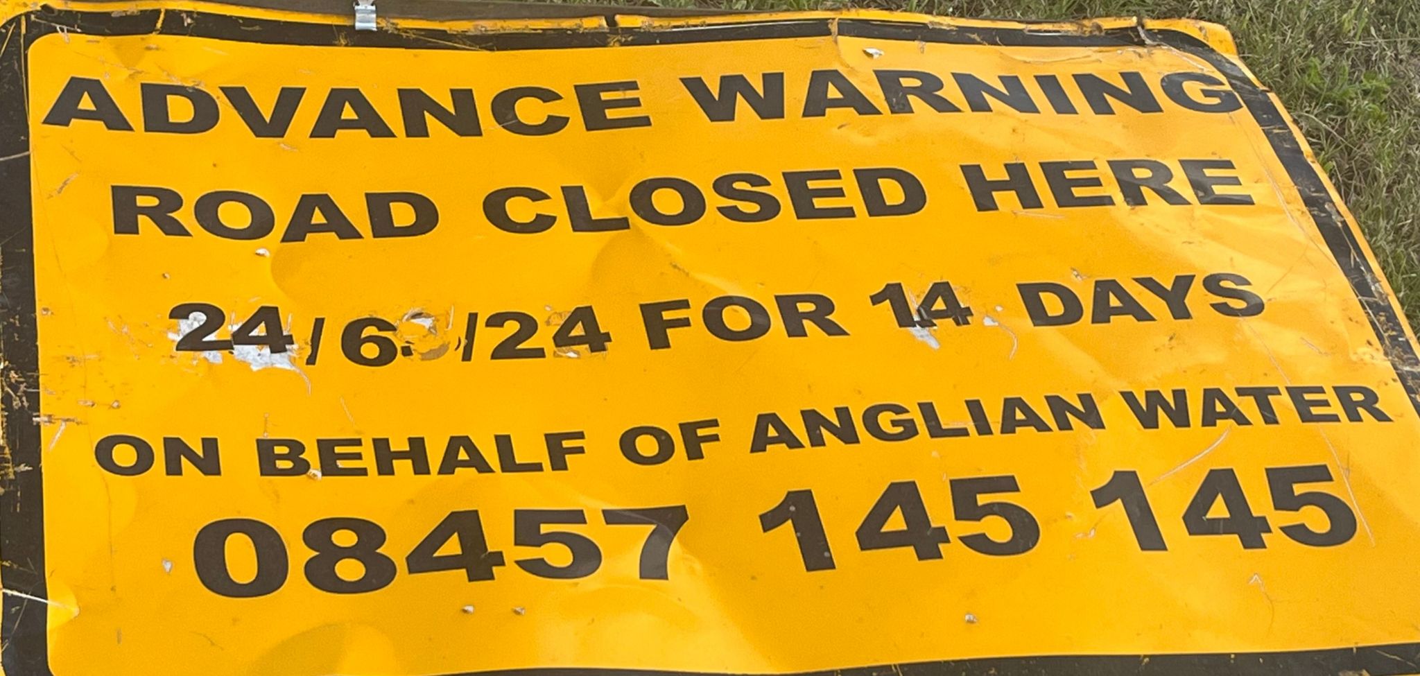 A sign saying 'Advance warning road closed here. 24/6/24 for 14 days on behalf of Anglian Water 08457 145 145'