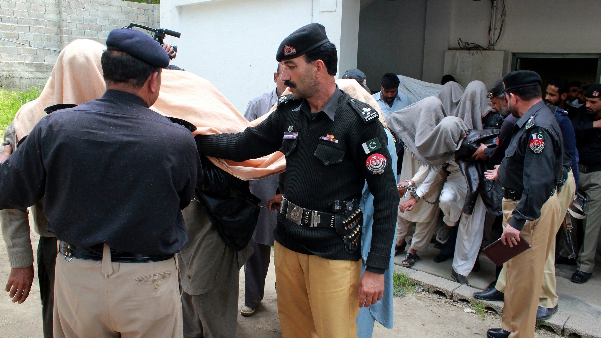 Police lead away arrested members of the jirga outside a court in Abbottabad, Pakistan. 5 May 2016