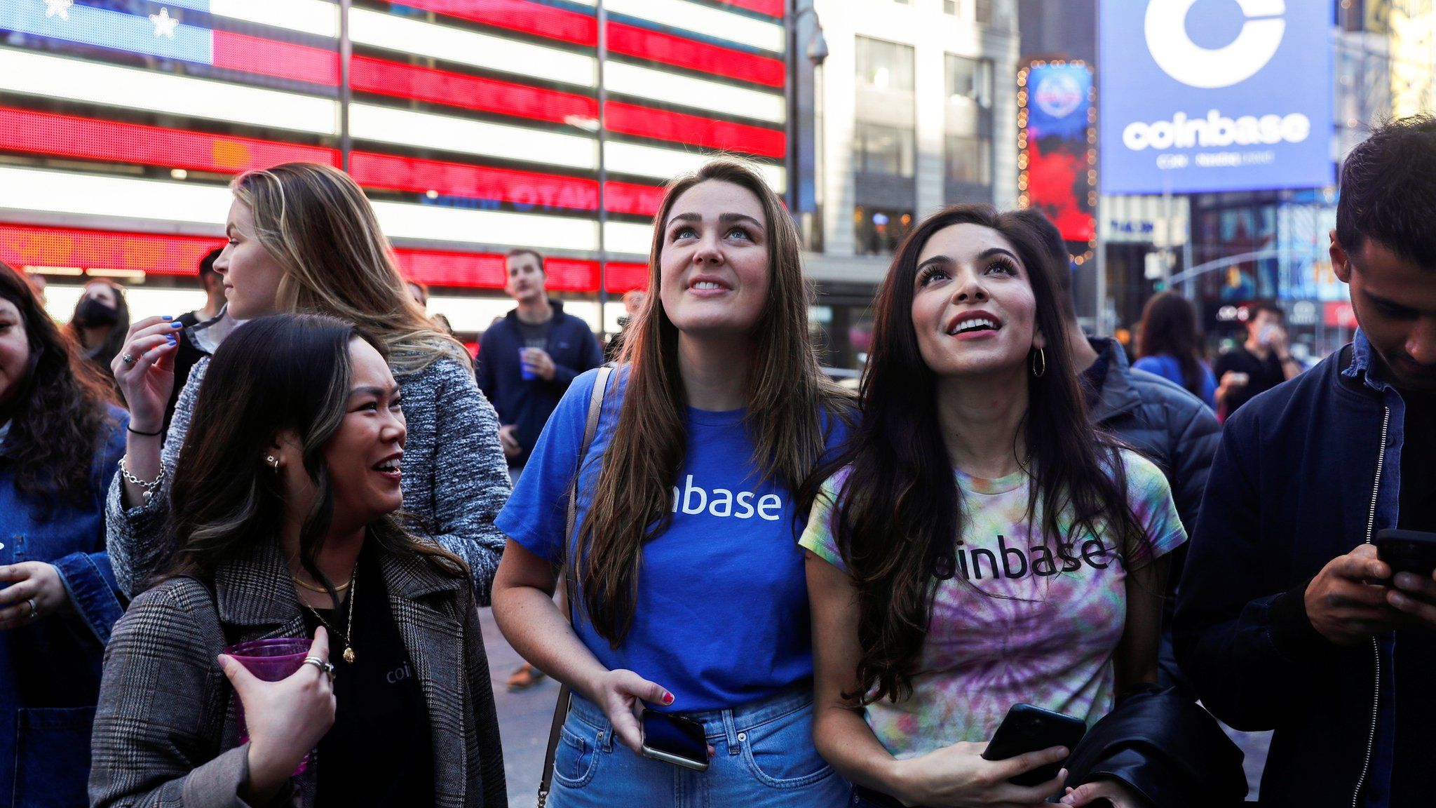 Employees of Coinbase Global Inc, the biggest U.S. cryptocurrency exchange, watch as their listing is displayed on the Nasdaq MarketSite jumbotron at Times Square in New York, U.S., April 14, 2021