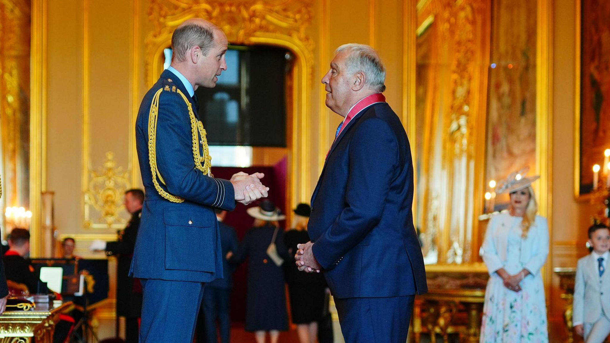 The Prince of Wales talking to Peter Shilton after appointing him CBE at a gold-coloured Windsor Castle reception room
