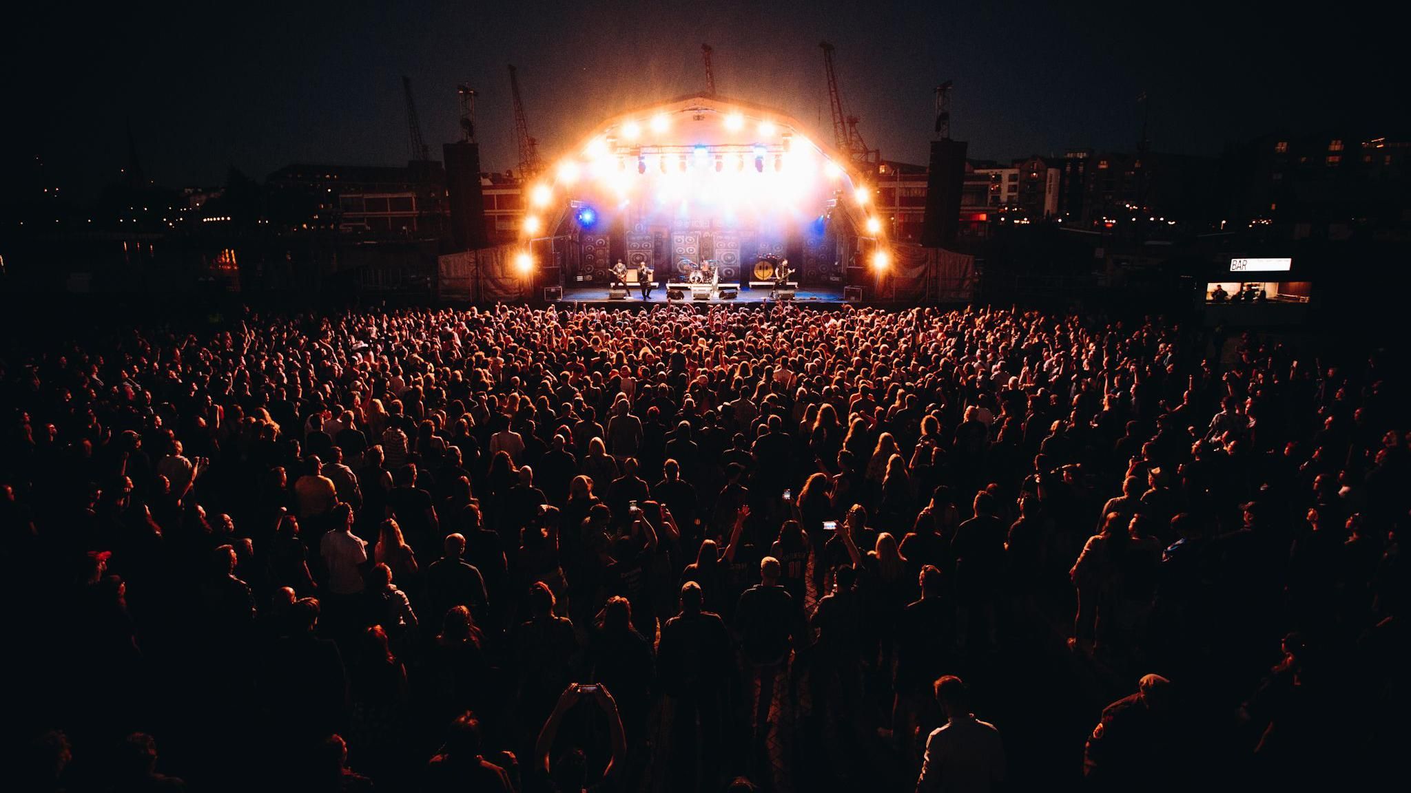 A crowd at Bristol Sounds 2024 illuminated by the stage lights