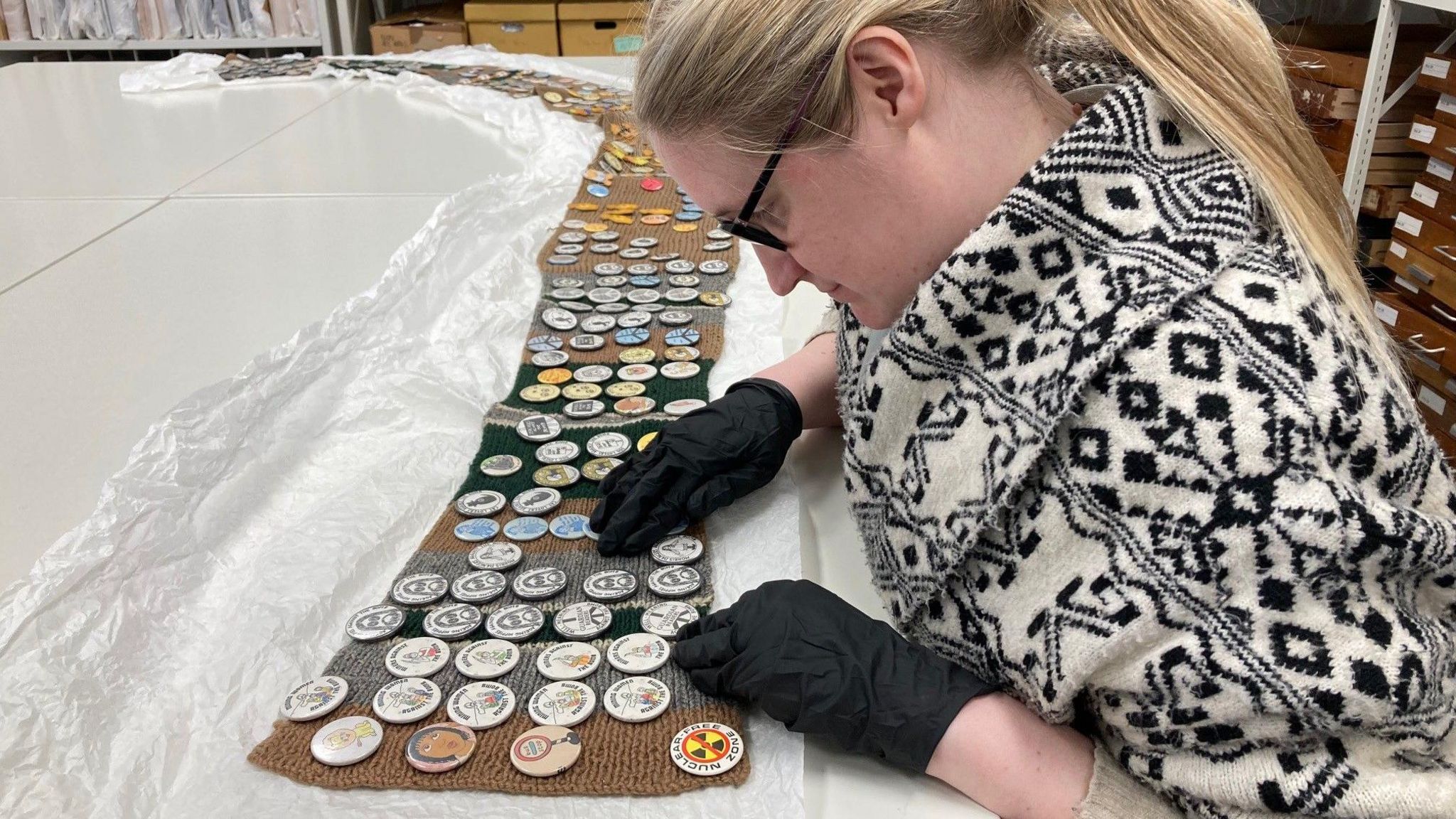 Curator Charlotte Houlahan looks at historic peace pin badges.