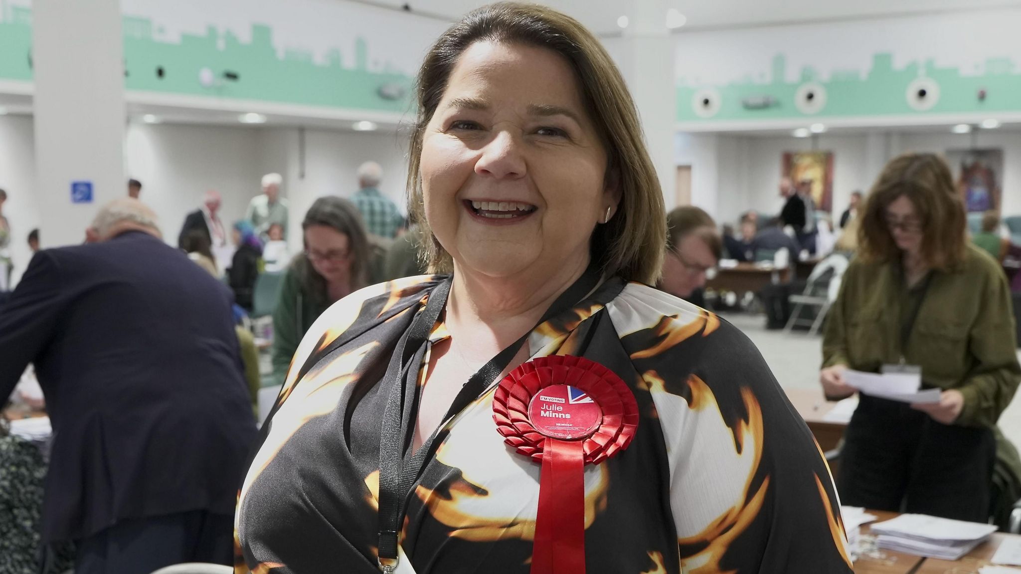 Winning Labour candidate Julie Minns wearing a red rosette smiles at the camera