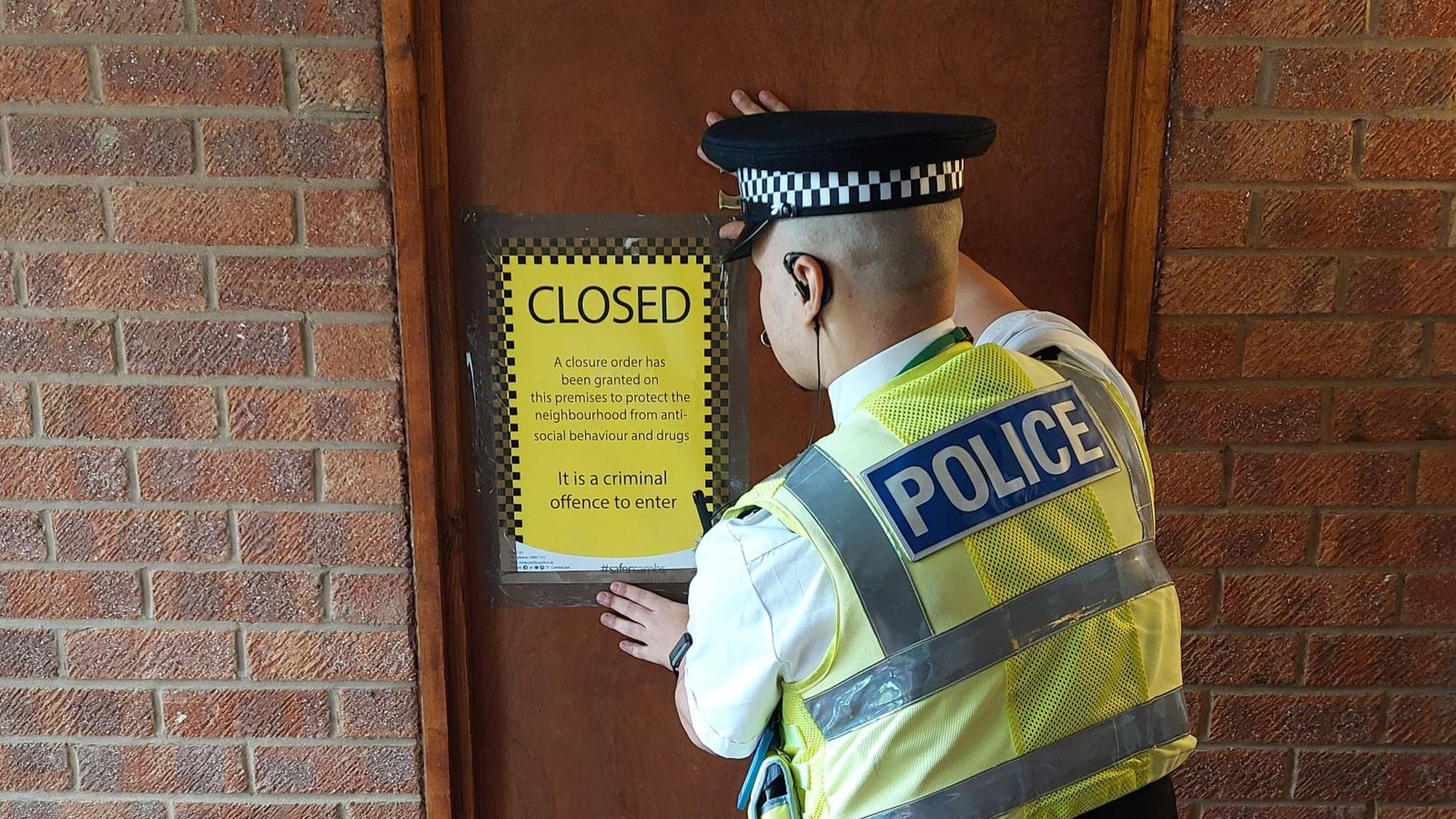Police officer putting a sign on a door