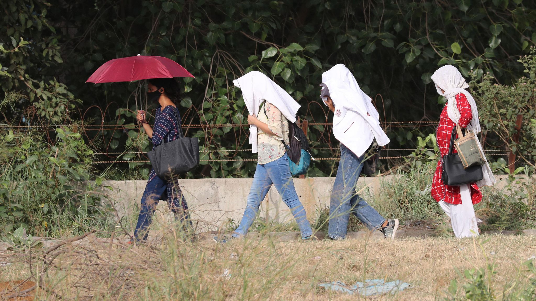 Indian girls use their white jackets and umbrella to protect themselves from the sun during a heatwave near New Delhi, India, 22 May 2023. India Meteorological Department issued a heat wave warning after several parts of the Indian capital recorded maximum temperatures above 45 degrees Celsius. Heatwave warning issued for several parts of India, New Delhi - 22 May 2023