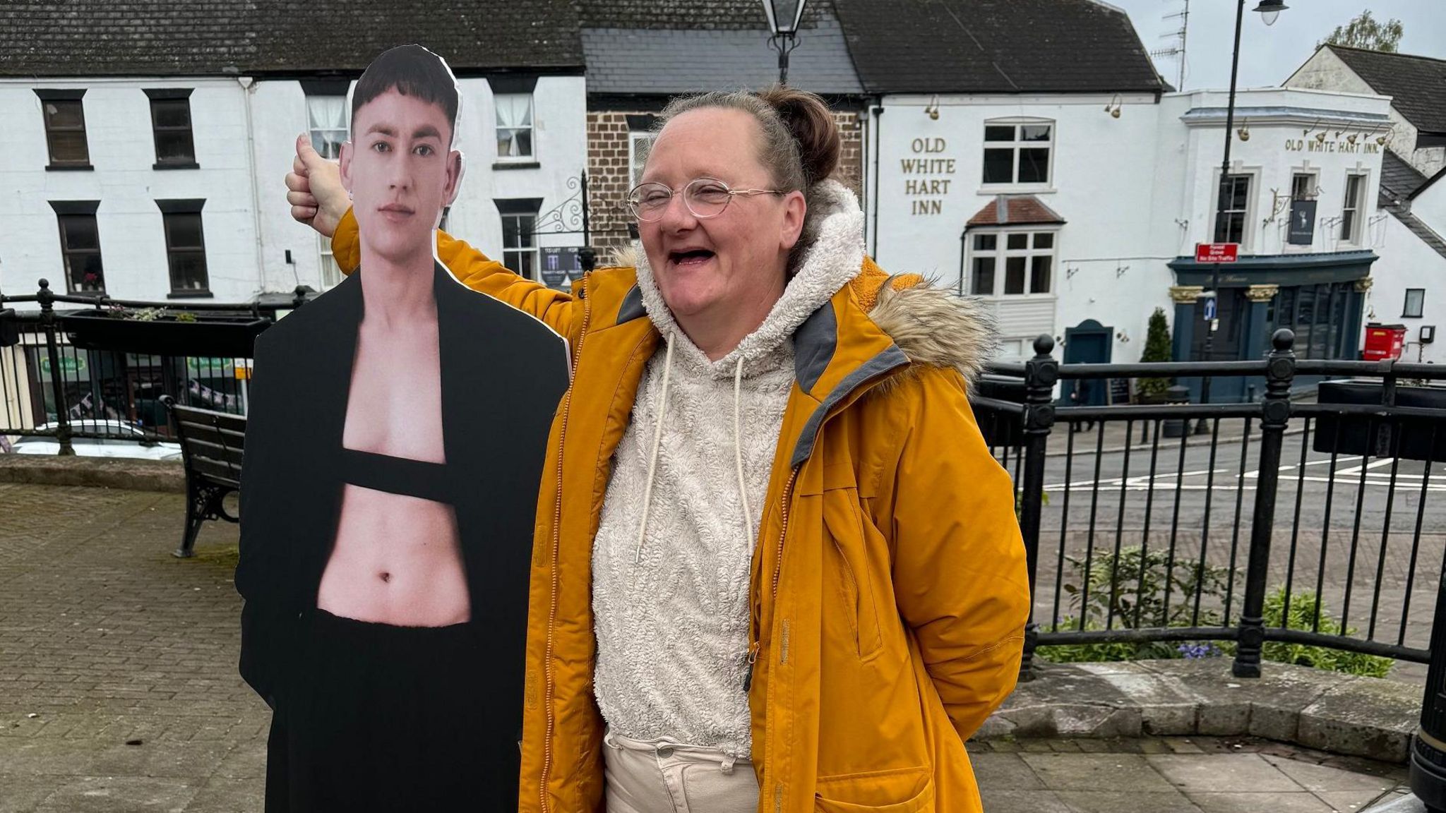 Woman in orange standing next to a cutout of Olly Alexander