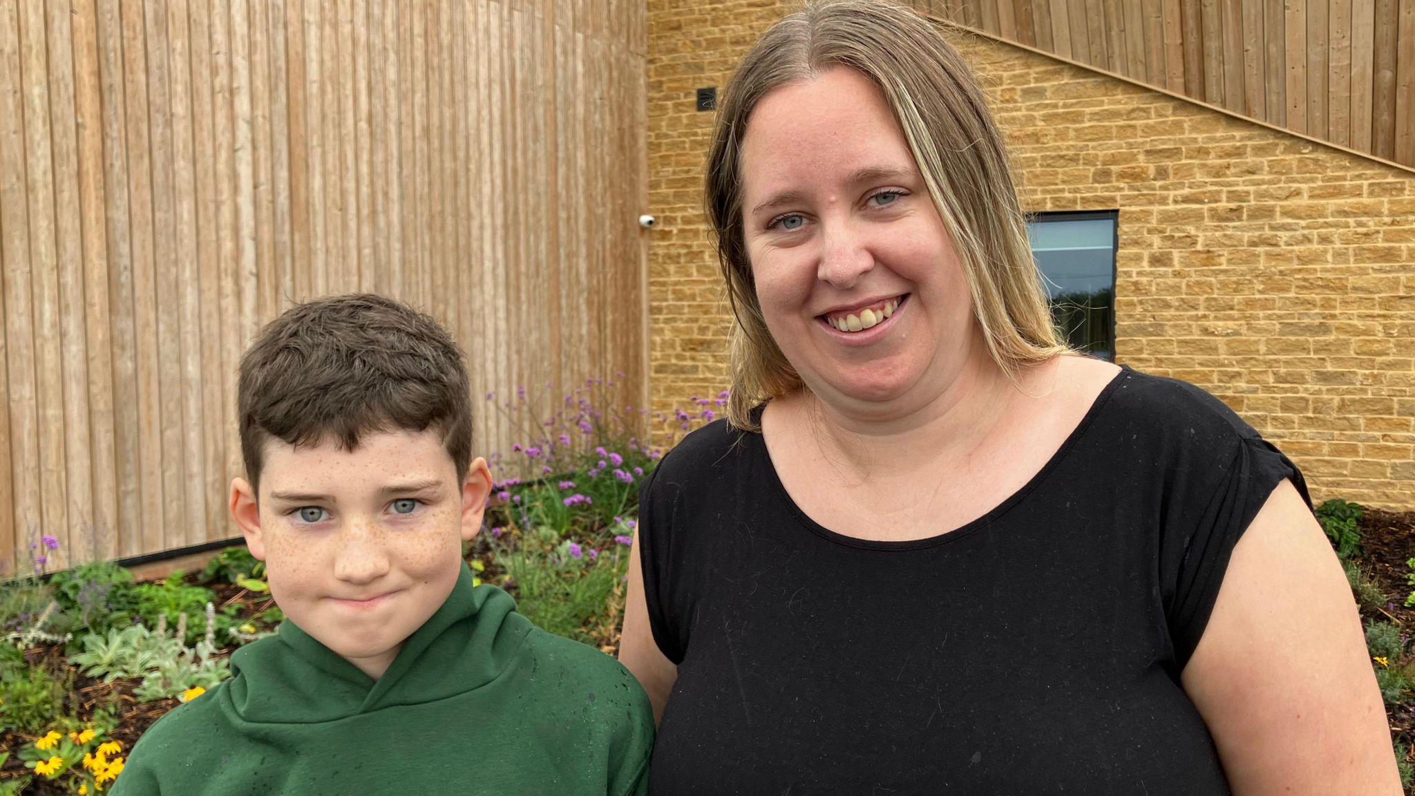 Ethan and his mum Leana smiling at the camera outside Hill View School