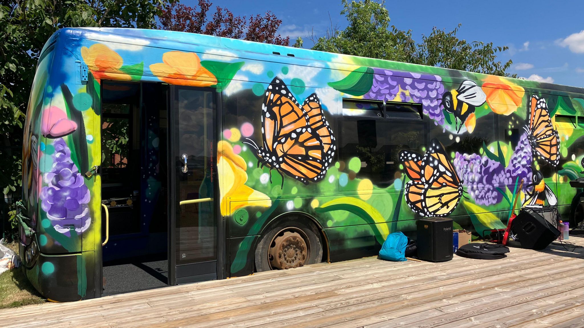 An old bus that has been painted with brightly coloured flowers and butterflies