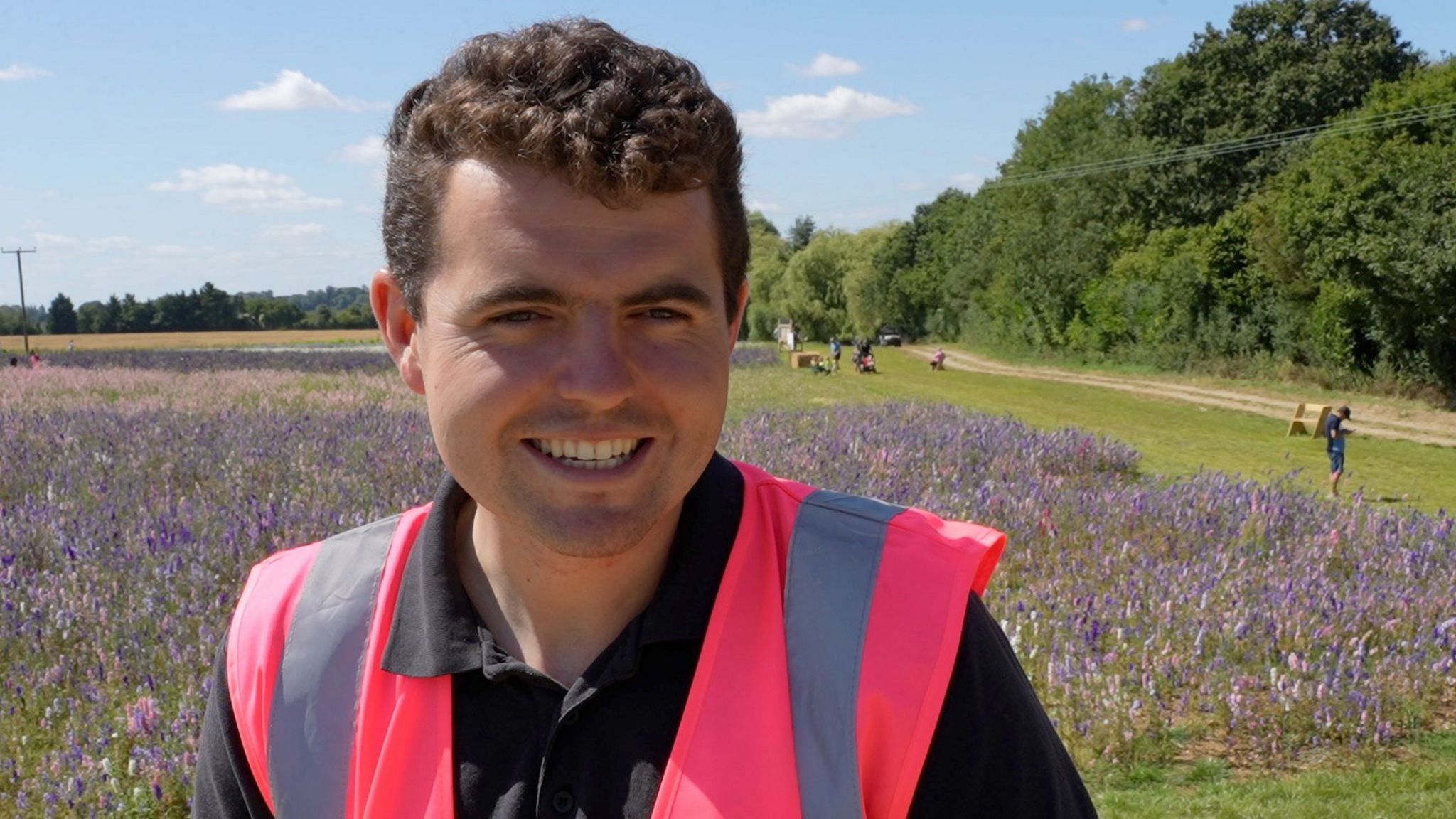 Man wearing high vis pink vest in front of flower field