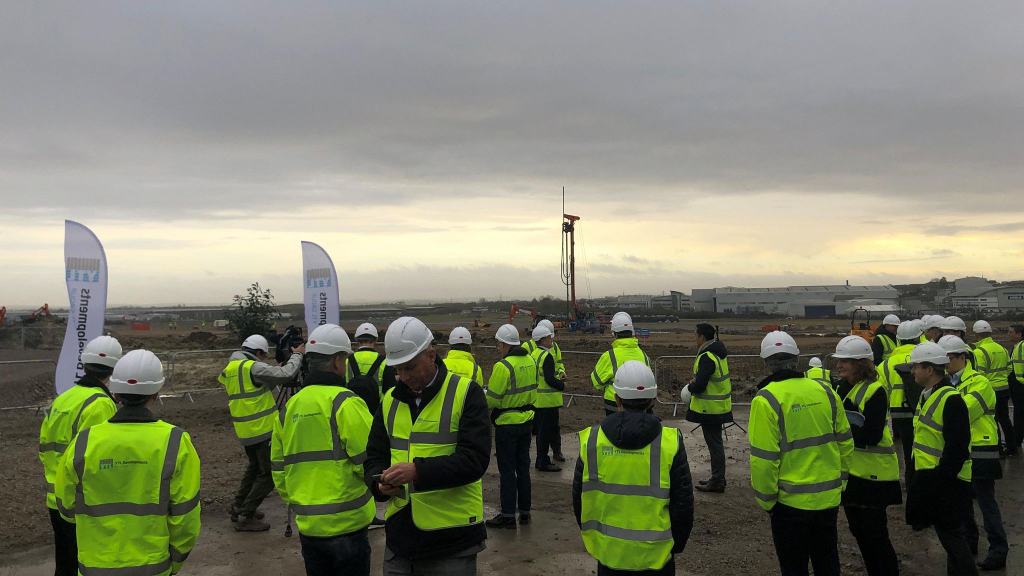 A gathering of people wearing hard hats and hi vis jackets on the site of Filton Airfield