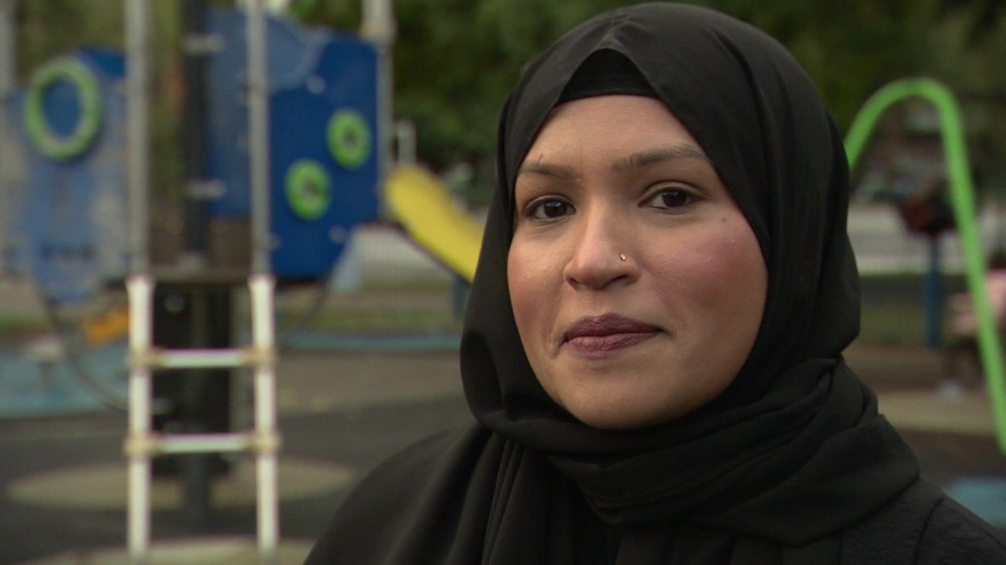 Hena Begum, a woman wearing a black hijab stood in front of a children's playground