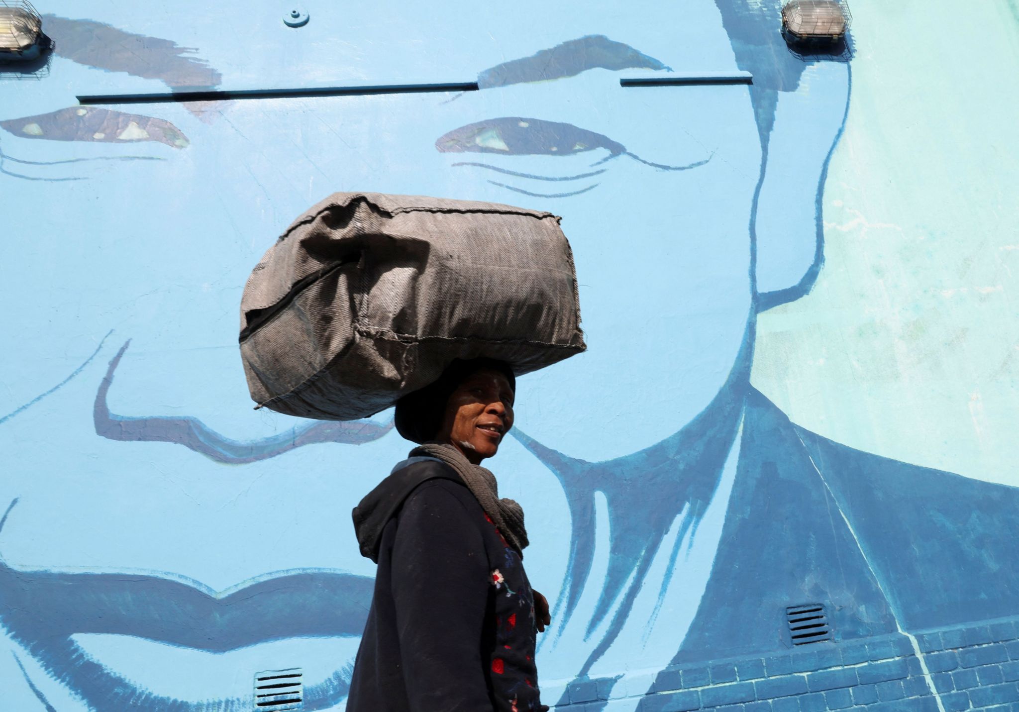 A woman walks past a mural depicting Nelson Mandela.