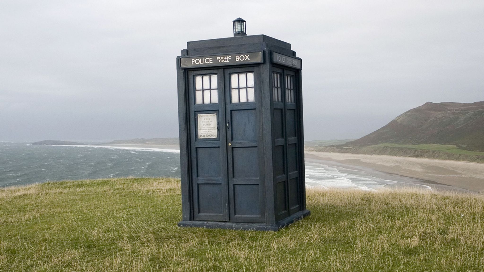 The TARDIS on a grassy hill overlooking the sea
© BBC