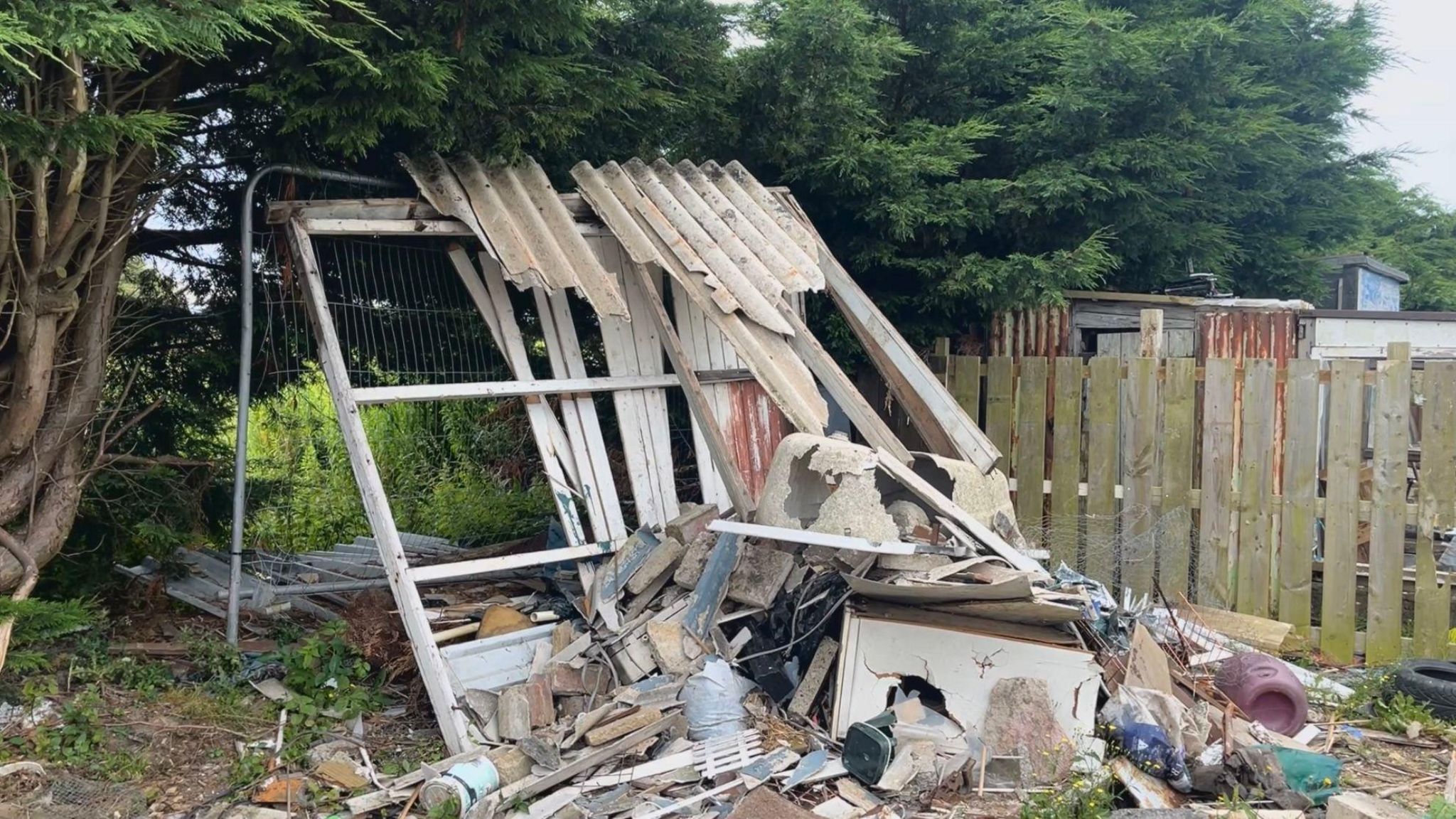 A pile of scrap and rubbish in the corner of one of the allotment plots.