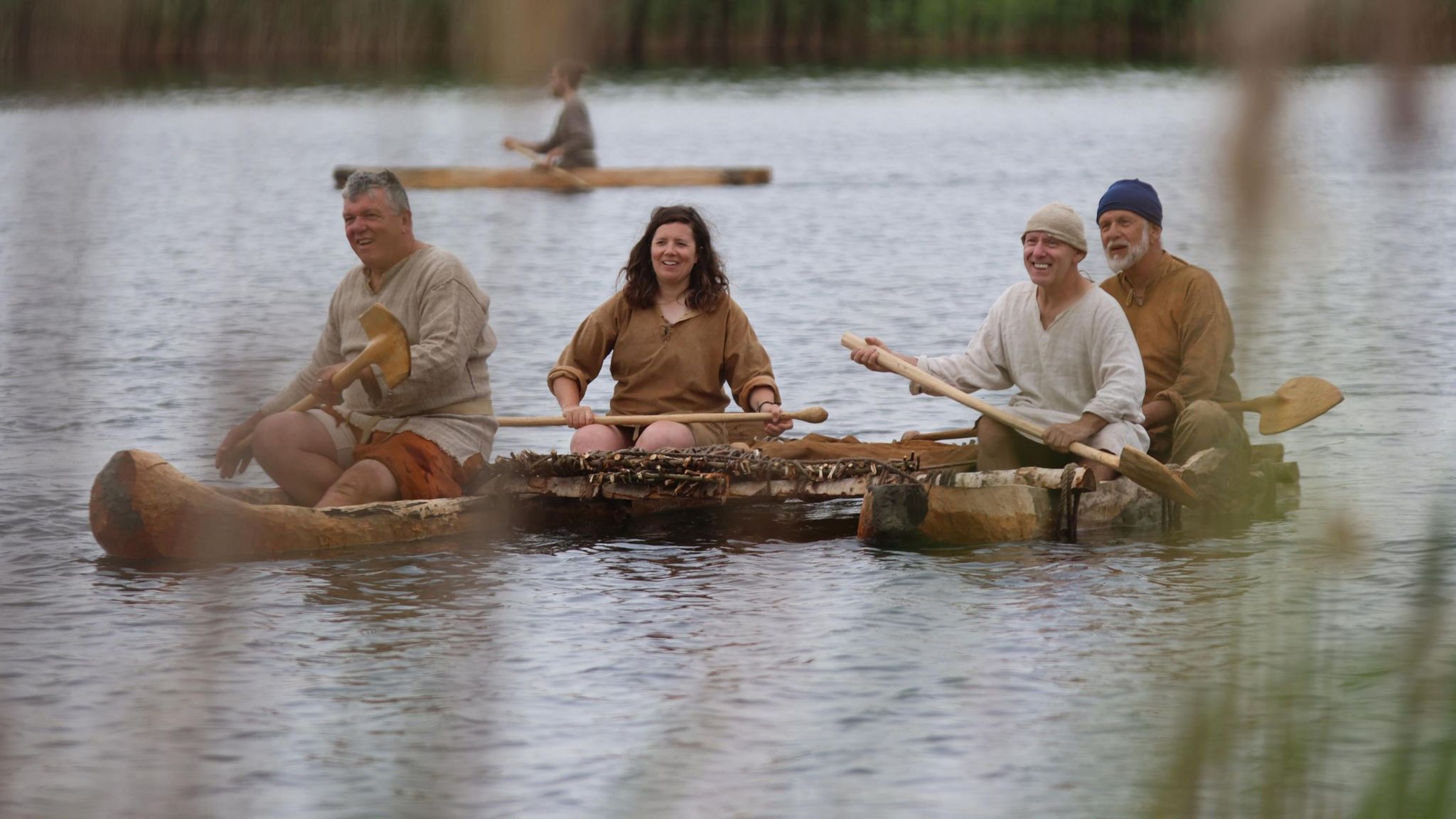 Three me and a woman rest their oars on a floating log boat